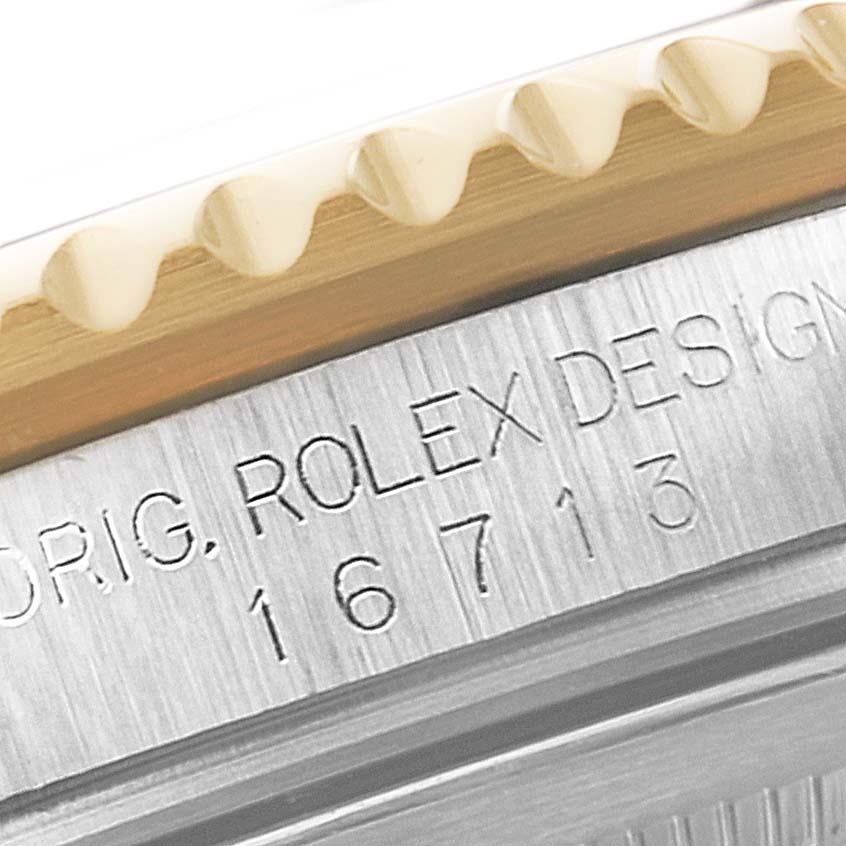 The image shows a close-up of the bezel and engraved serial number on a Rolex GMT-Master 16713 Men's Steel and Gold (two tone) Black Dial 16713 Men's Steel and Gold (two tone) Black Dial watch.