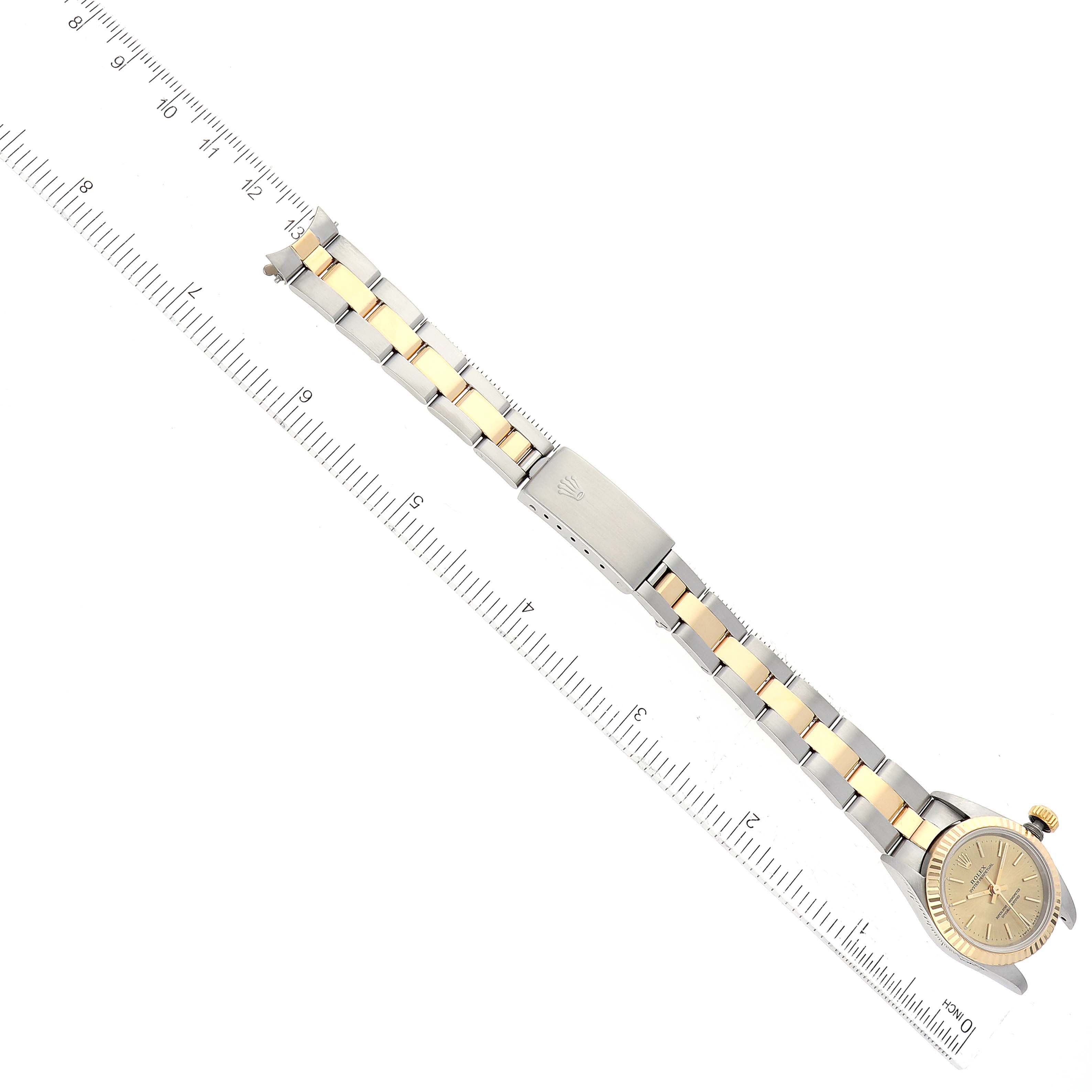 The image shows a top-down view of a Rolex Oyster Perpetual 67193 Women's Steel and Gold (two tone) Champagne Dial 67193 Women's Steel and Gold (two tone) Champagne Dial watch, displaying its face, bracelet, and clasp, alongside a ruler for scale.