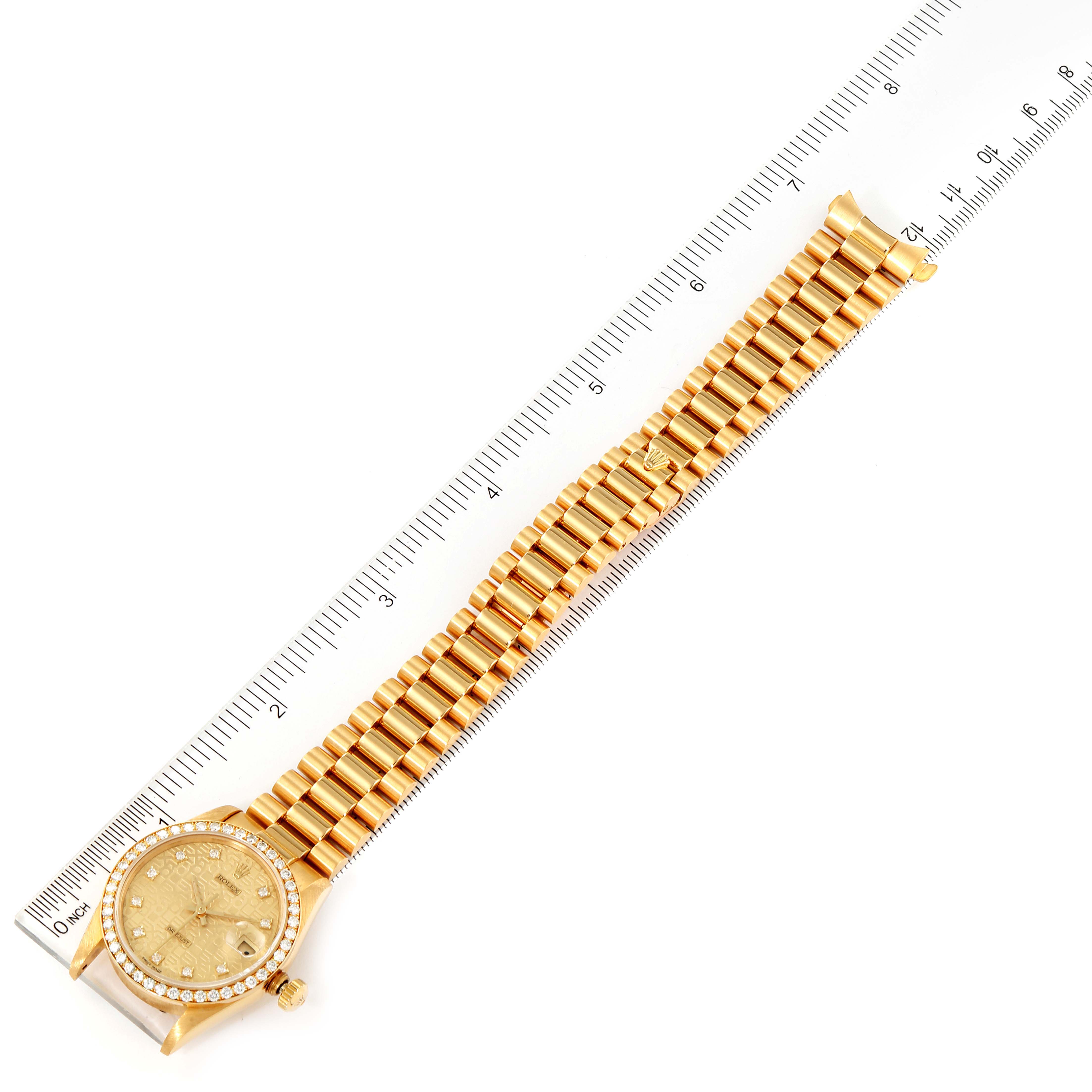 The image shows a top view of a gold Rolex President 68288 Women
s Yellow Gold Champagne Dial 68288 Women
s Yellow Gold Champagne Dial model watch with its band extended alongside a ruler.