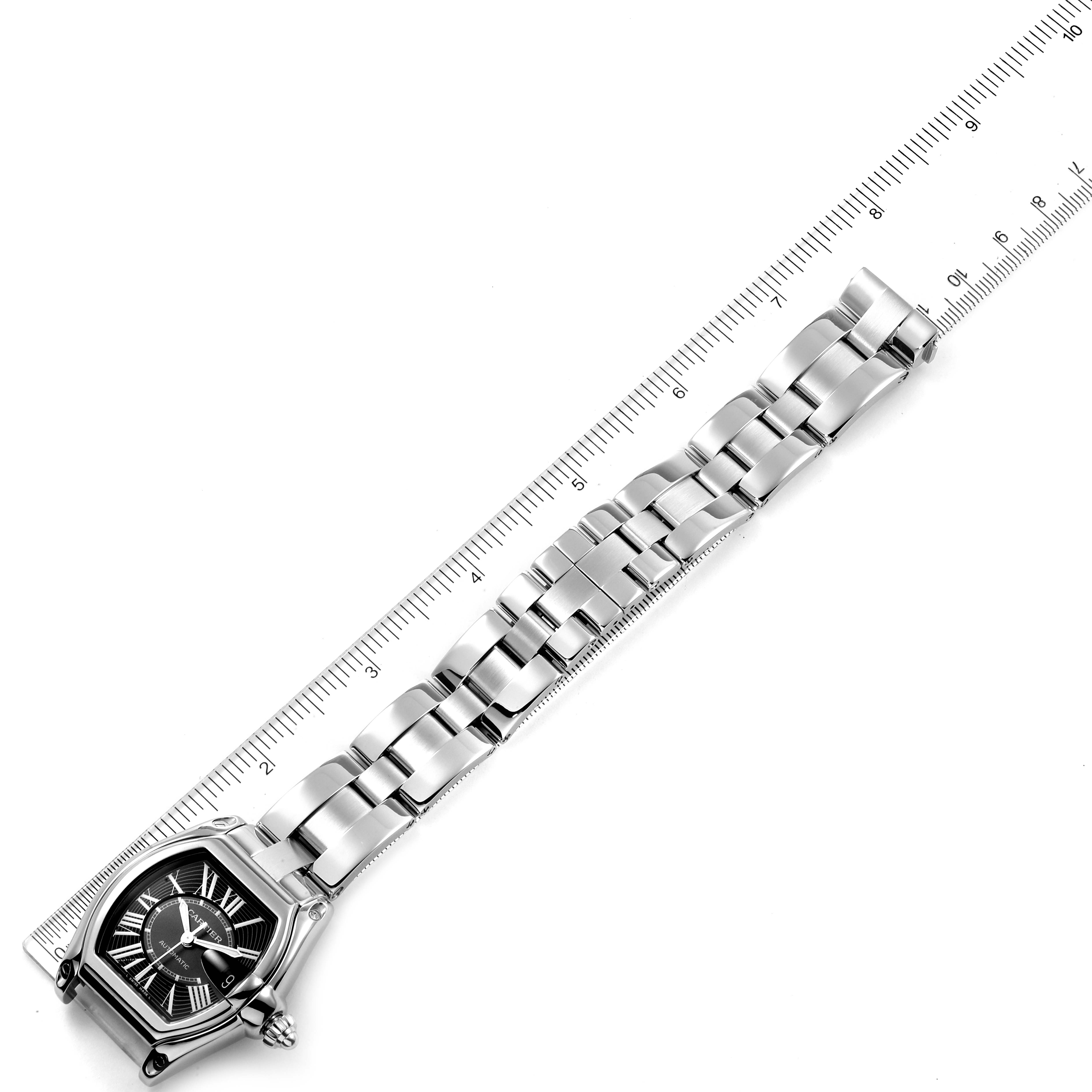 The image shows the Cartier Roadster W62041V3 Men
s Stainless Steel Black Dial W62041V3 Men
s Stainless Steel Black Dial watch diagonally with its face and metal bracelet aligned with a ruler.