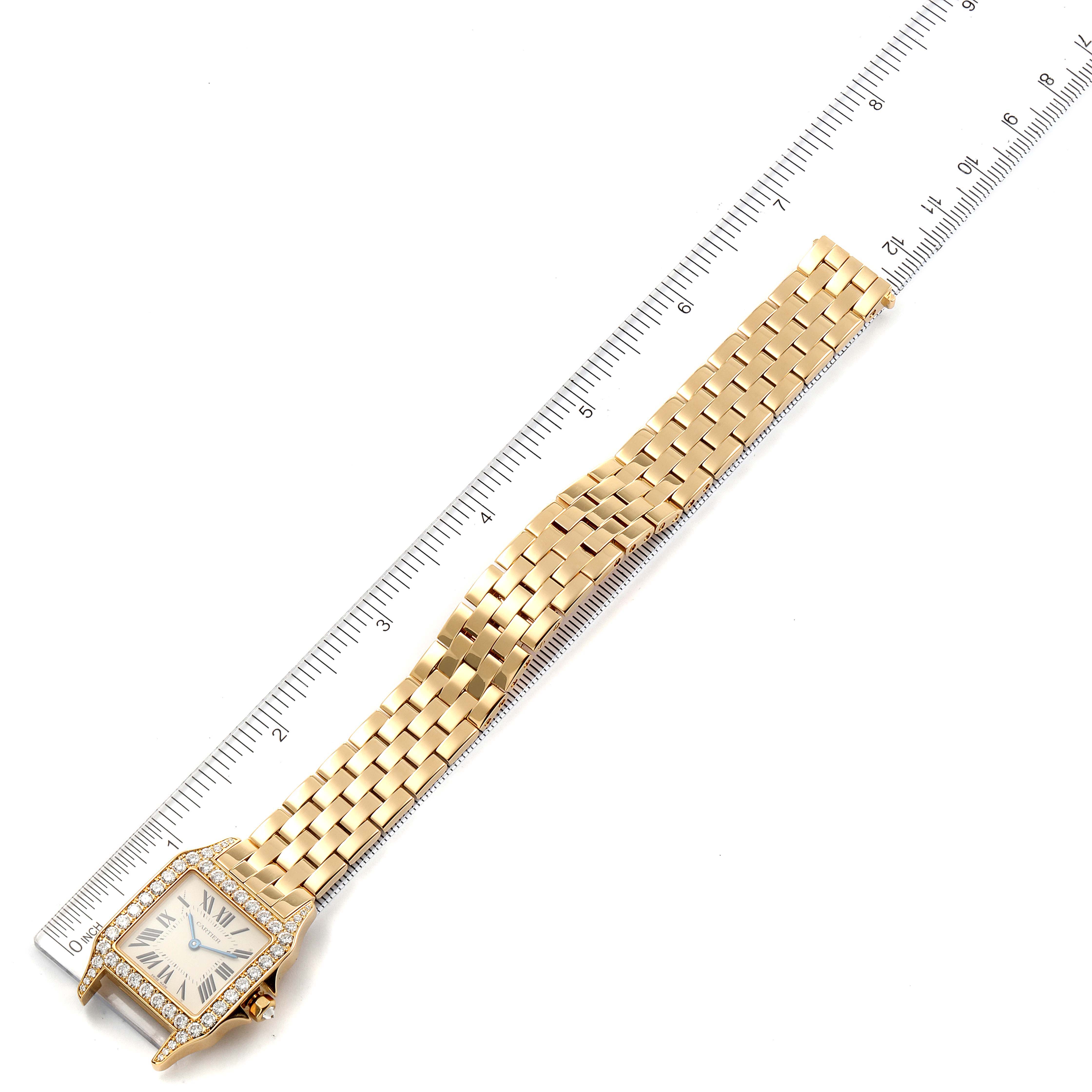 The Cartier Santos WF9002Y7 Men's Yellow Gold Silver Dial WF9002Y7 Men's Yellow Gold Silver Dial watch is shown at a top-down angle, including the face, bezel, and full bracelet, with a ruler for scale.