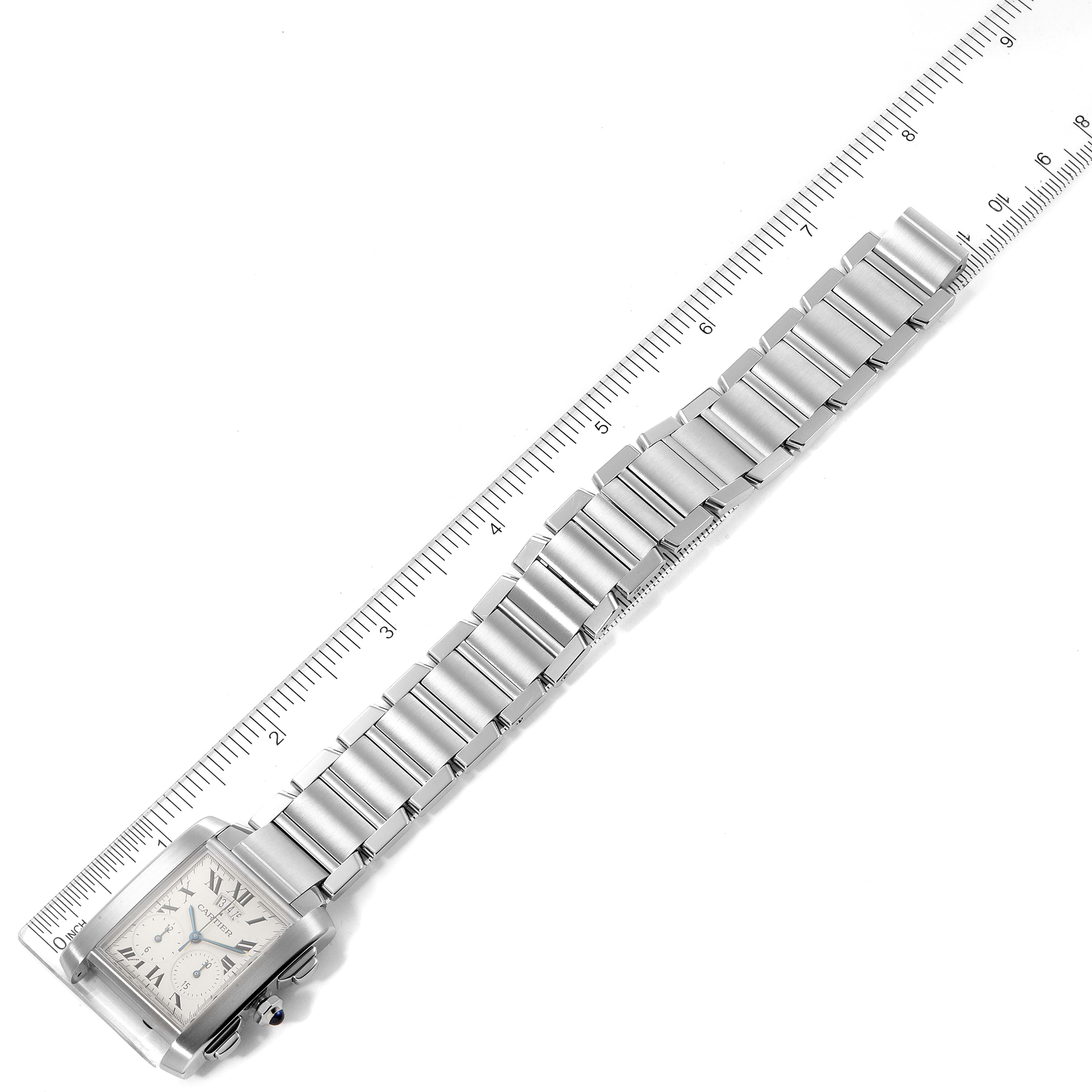 The image shows a Cartier Tank Francaise W51024Q3 Men's Stainless Steel Silver Dial W51024Q3 Men's Stainless Steel Silver Dial watch laying flat next to a ruler, highlighting its metal bracelet and square face.