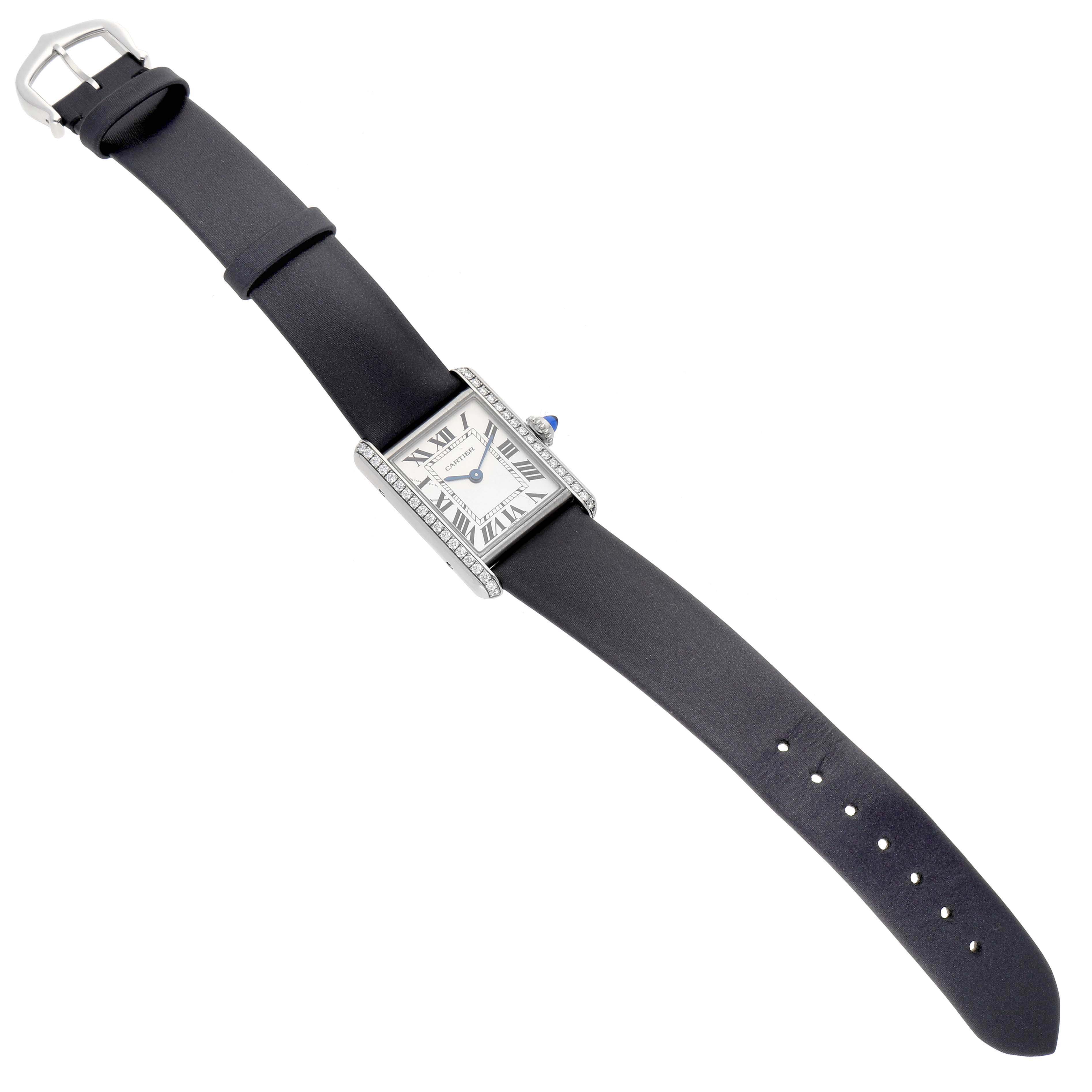 The Tank Must by Cartier is shown from a top-down angle, displaying the watch face, bezel, strap, and buckle.