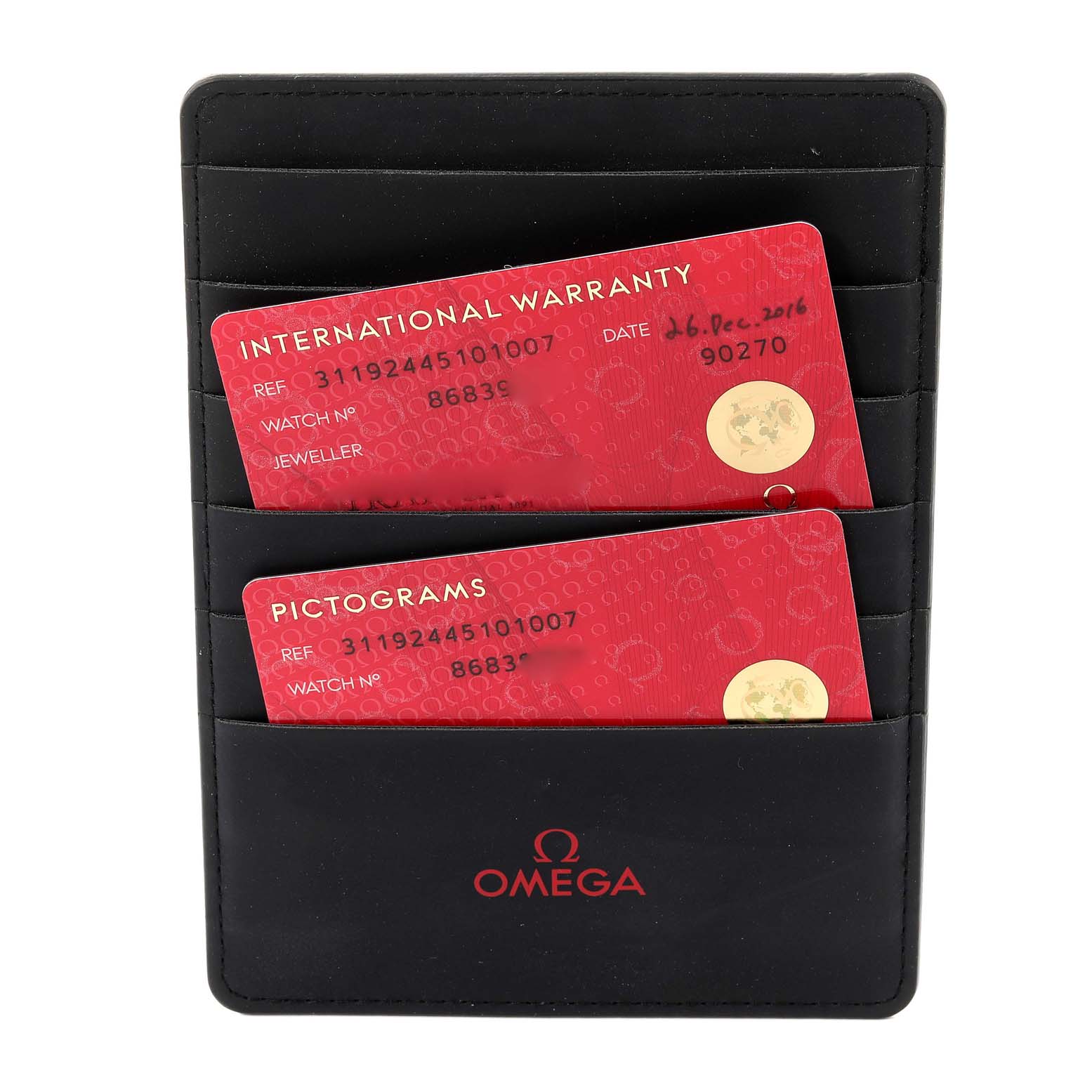 The image shows two red cards, an International Warranty and Pictograms card, inside a black Omega holder for a Speedmaster model.