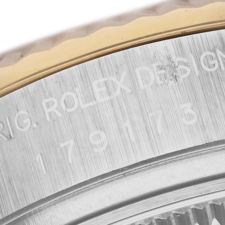 The image shows a close-up of the bezel and part of the casing of a Rolex Datejust 179173 Women's Steel and Gold (two tone) Silver Dial 179173 Women's Steel and Gold (two tone) Silver Dial watch, highlighting engraved text.