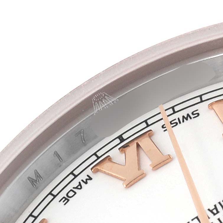 The image shows a close-up of the dial and bezel of a Mid-Size Rolex watch, featuring Roman numerals and part of the minute hand.