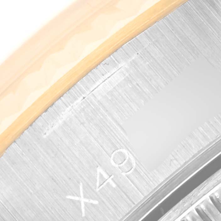 This close-up photograph of a Rolex Datejust 69173 Women's Steel and Gold (two tone) Champagne Dial 69173 Women's Steel and Gold (two tone) Champagne Dial watch focuses on its edge, showing part of the bezel and engraved serial details.