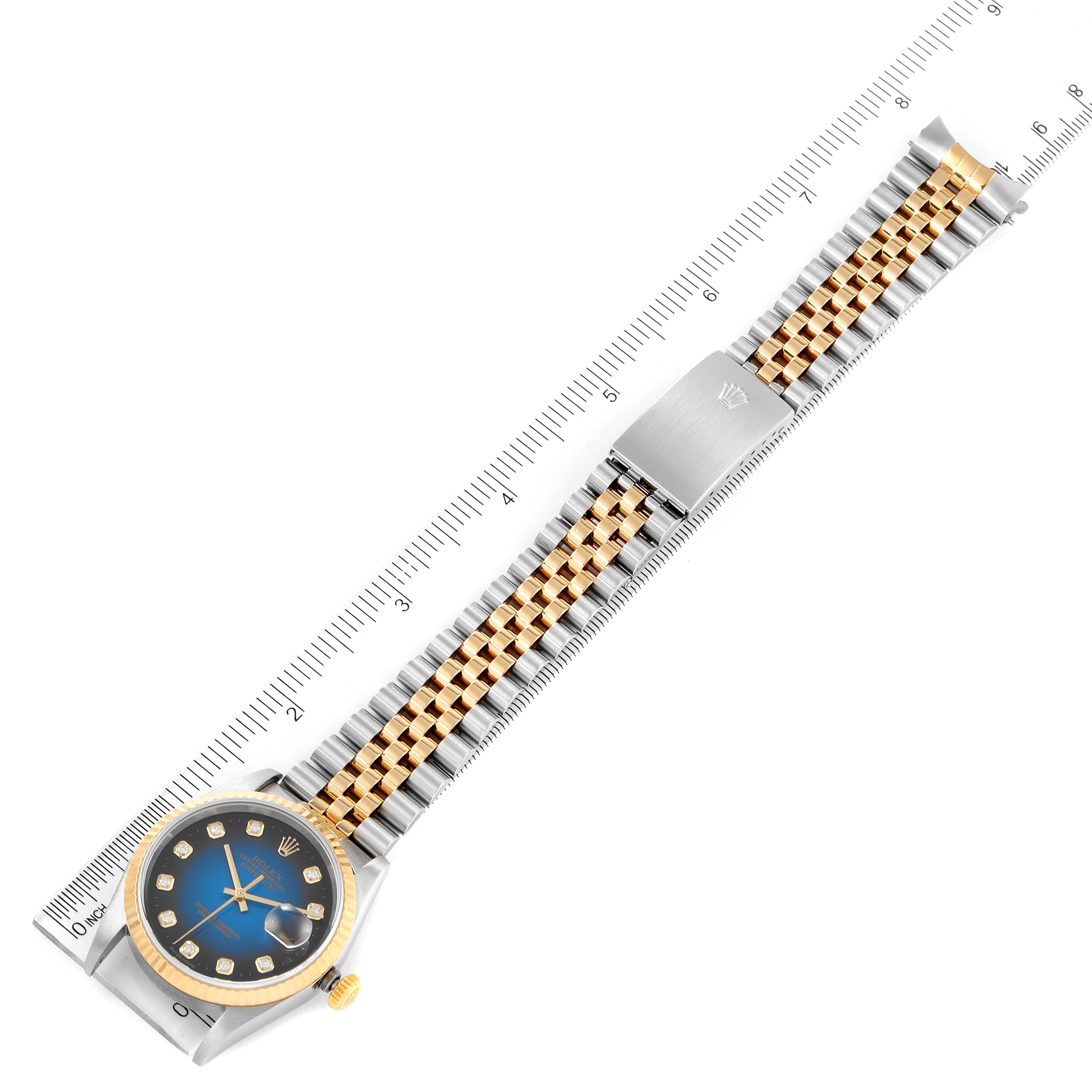 The image shows a Rolex Datejust 16233 Men's Steel and Gold (two tone) Blue Dial 16233 Men's Steel and Gold (two tone) Blue Dial watch laid flat with a focus on its face, bracelet, and clasp, alongside a measuring ruler.