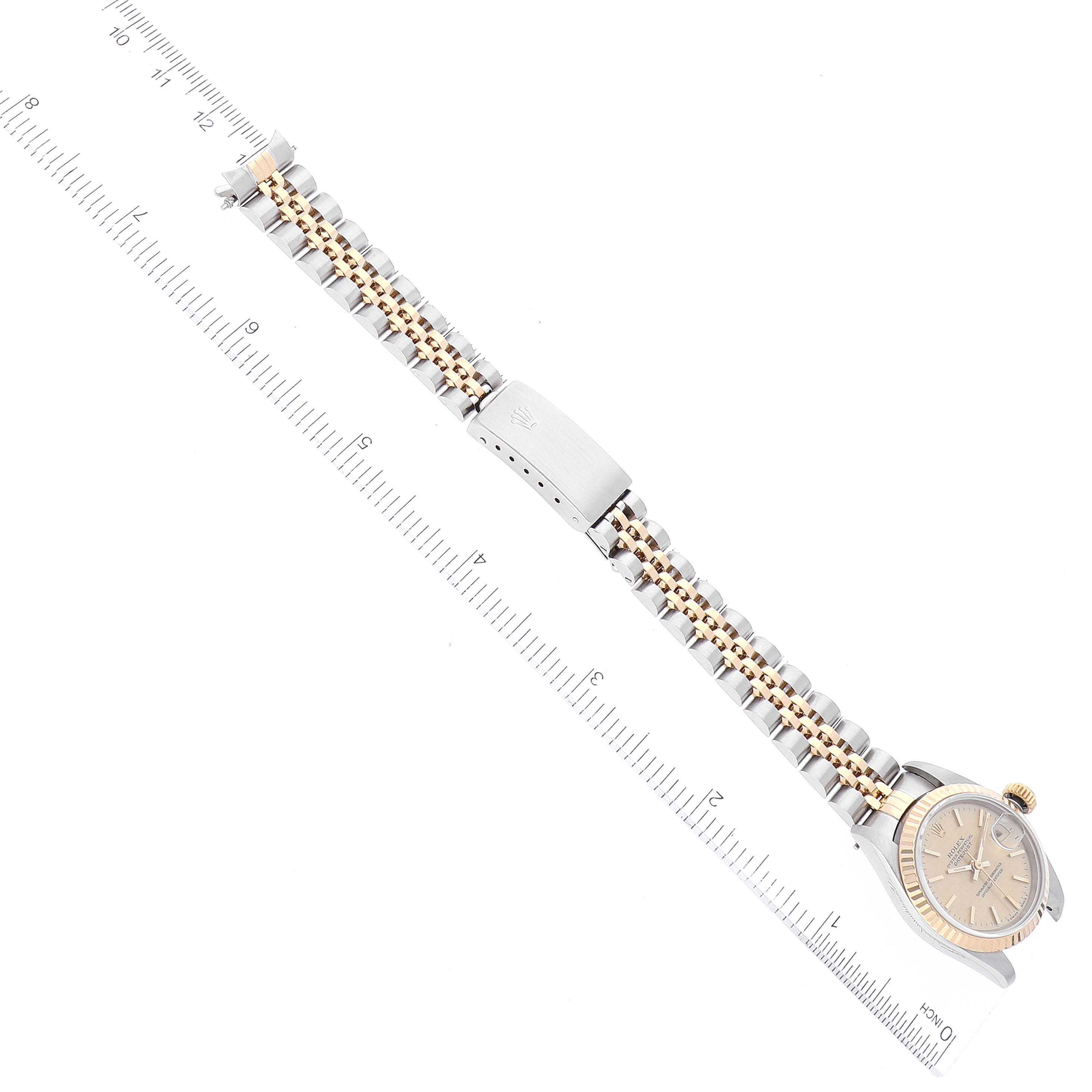 The image shows a top view of a Rolex Datejust 69173 Women's Steel and Gold (two tone) Champagne Dial 69173 Women's Steel and Gold (two tone) Champagne Dial watch with a gold and silver jubilee bracelet and a ruler for scale.