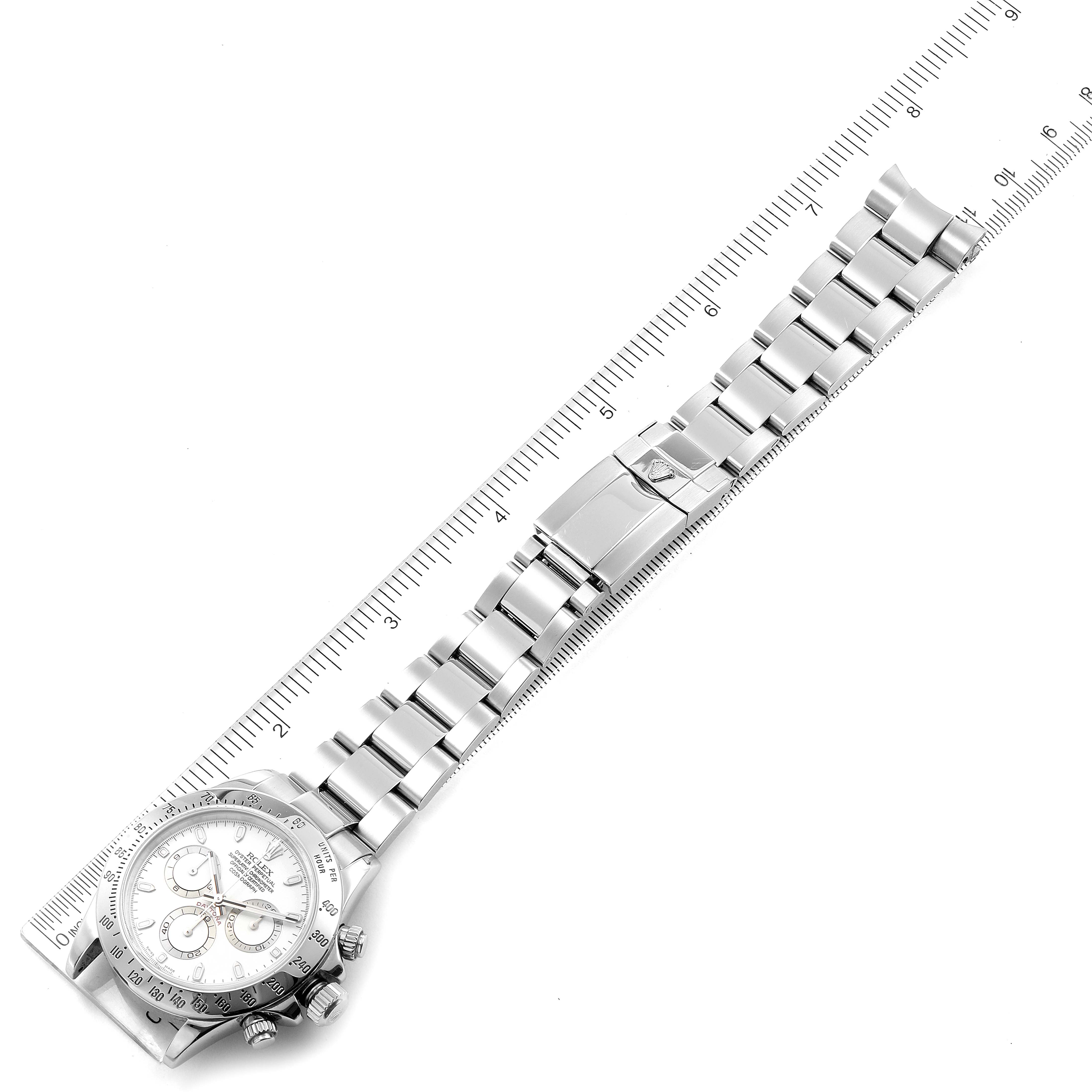 This image shows a top view of a Rolex Daytona 116520 Men's Stainless Steel White Dial 116520 Men's Stainless Steel White Dial watch displaying its face, bezel, and bracelet alongside a ruler for scale.