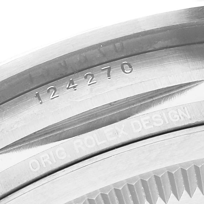 The image shows the side angle of a Rolex Explorer 124270 Men
s Stainless Steel Black Dial 124270 Men
s Stainless Steel Black Dial watch, focusing on the engraved model number and "ORIG. ROLEX DESIGN."