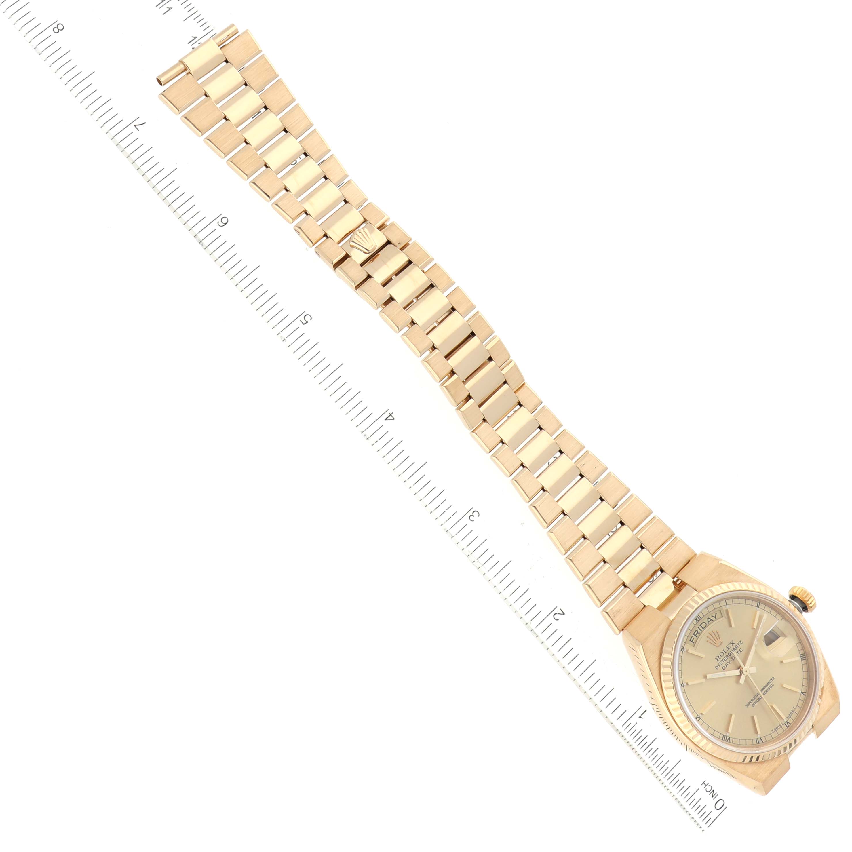 The Rolex President 19018 Men
s Yellow Gold Champagne Dial 19018 Men
s Yellow Gold Champagne Dial model watch is shown from an overhead angle displaying its face and full bracelet alongside a measuring ruler.