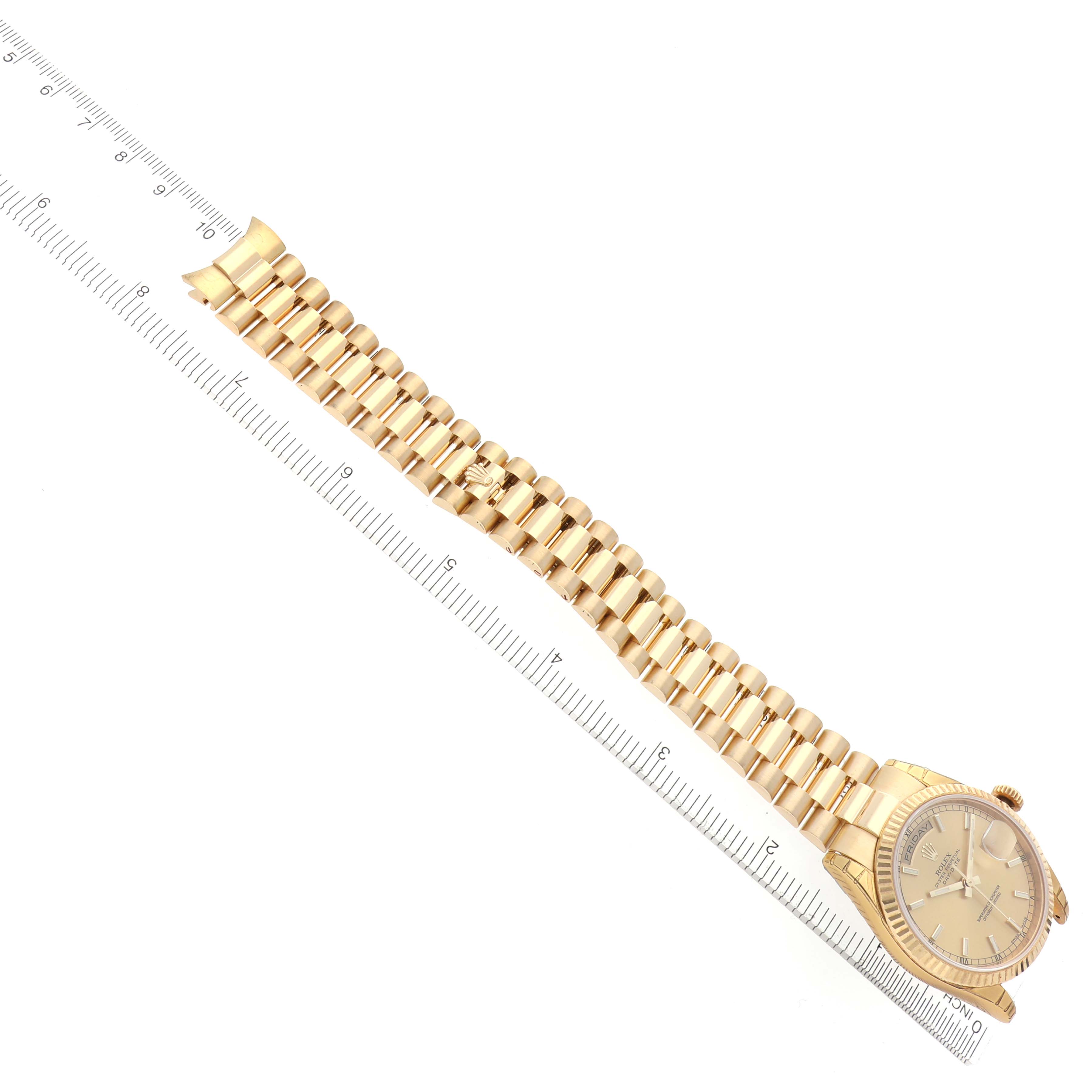 The Rolex President 118238 Men
s Yellow Gold Champagne Dial 118238 Men
s Yellow Gold Champagne Dial model watch is shown from a top-down angle, displaying its entire bracelet and face beside a ruler.