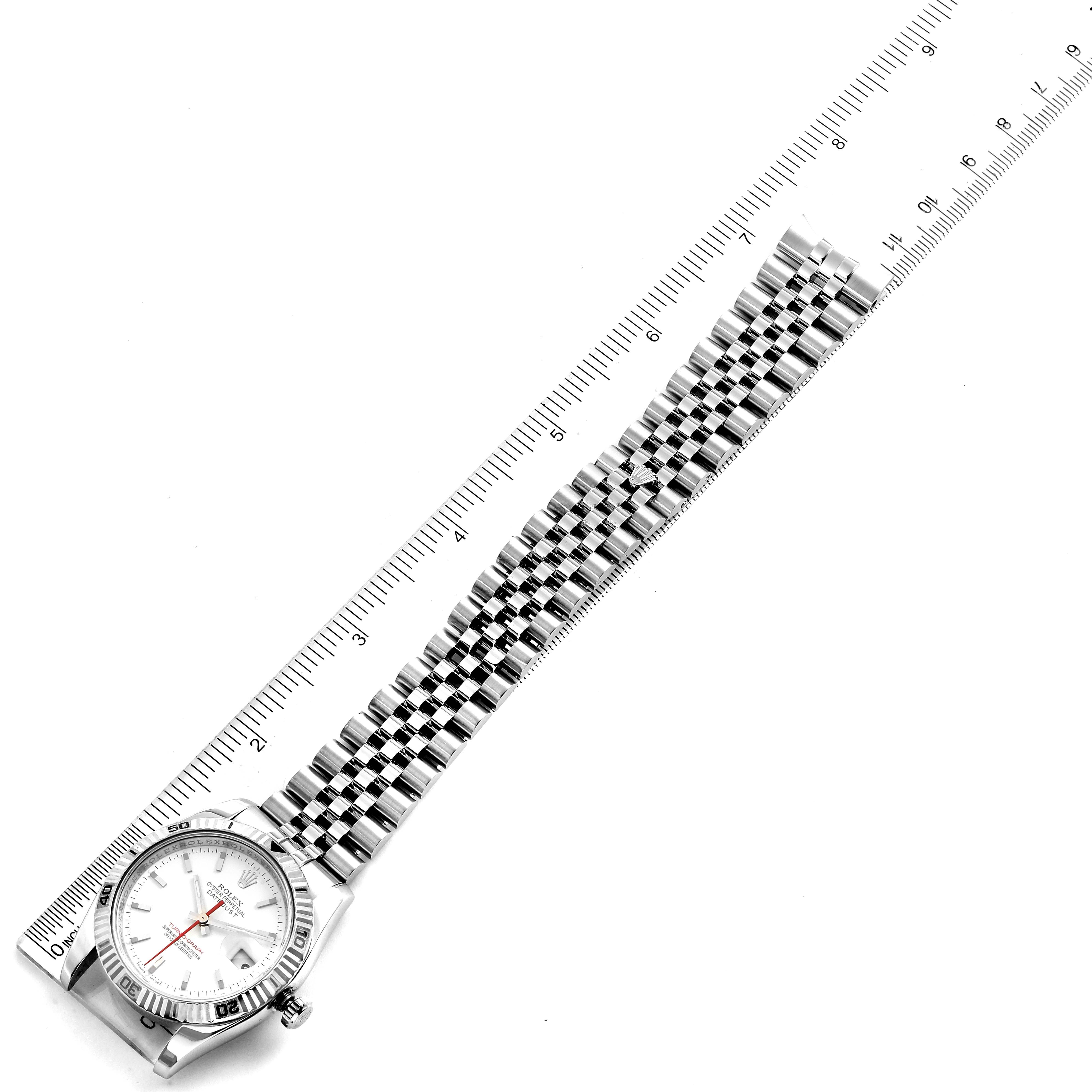 The Rolex Turn-o-Graph 116264 Men
s Stainless Steel White Dial 116264 Men
s Stainless Steel White Dial watch is shown laid flat next to a ruler, displaying the face, bezel, and full length of the bracelet.
