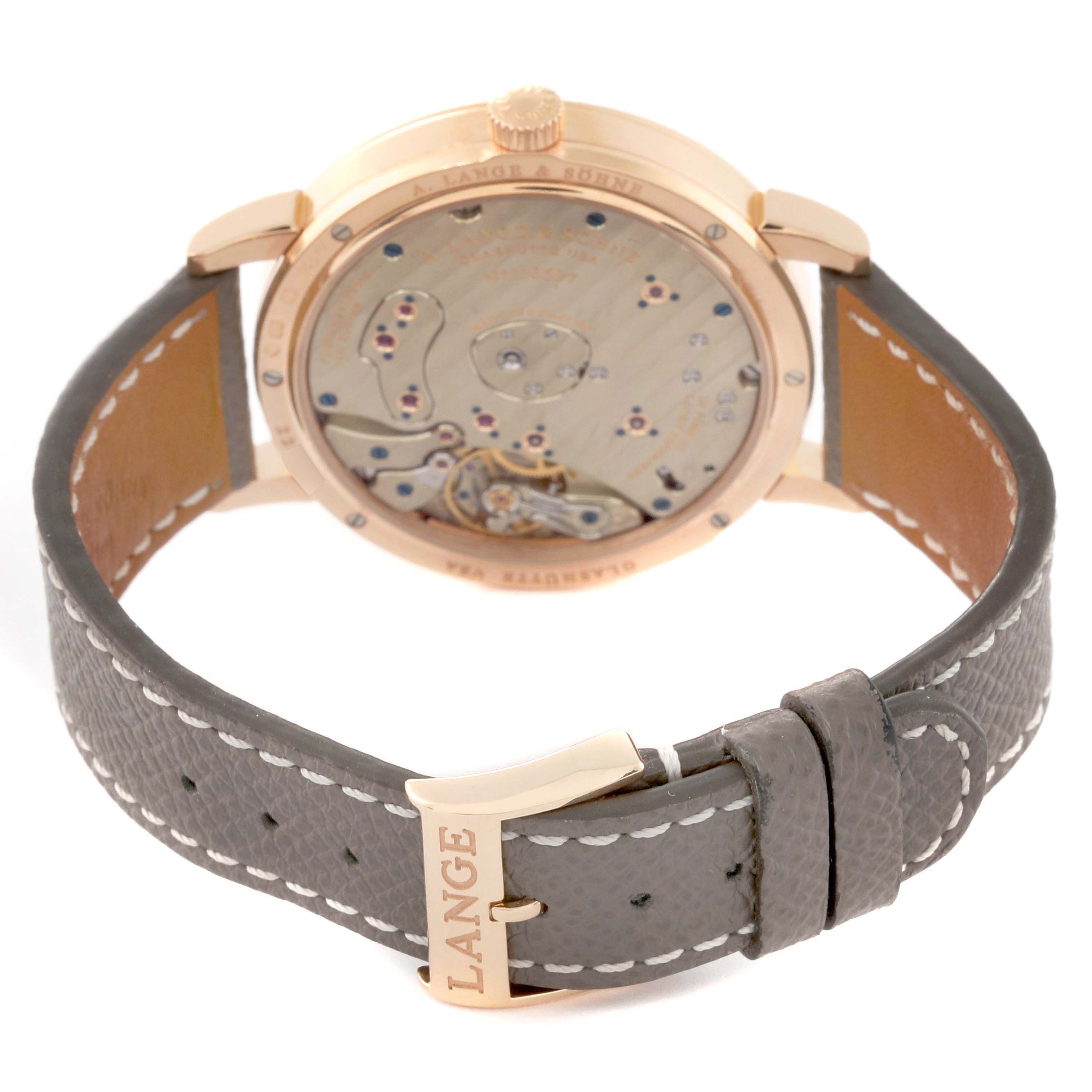 The image shows the back and side of the A. Lange & Sohne Lange 1 139.032 Men's Rose Gold Silver Dial watch, highlighting its movement and brown leather strap.