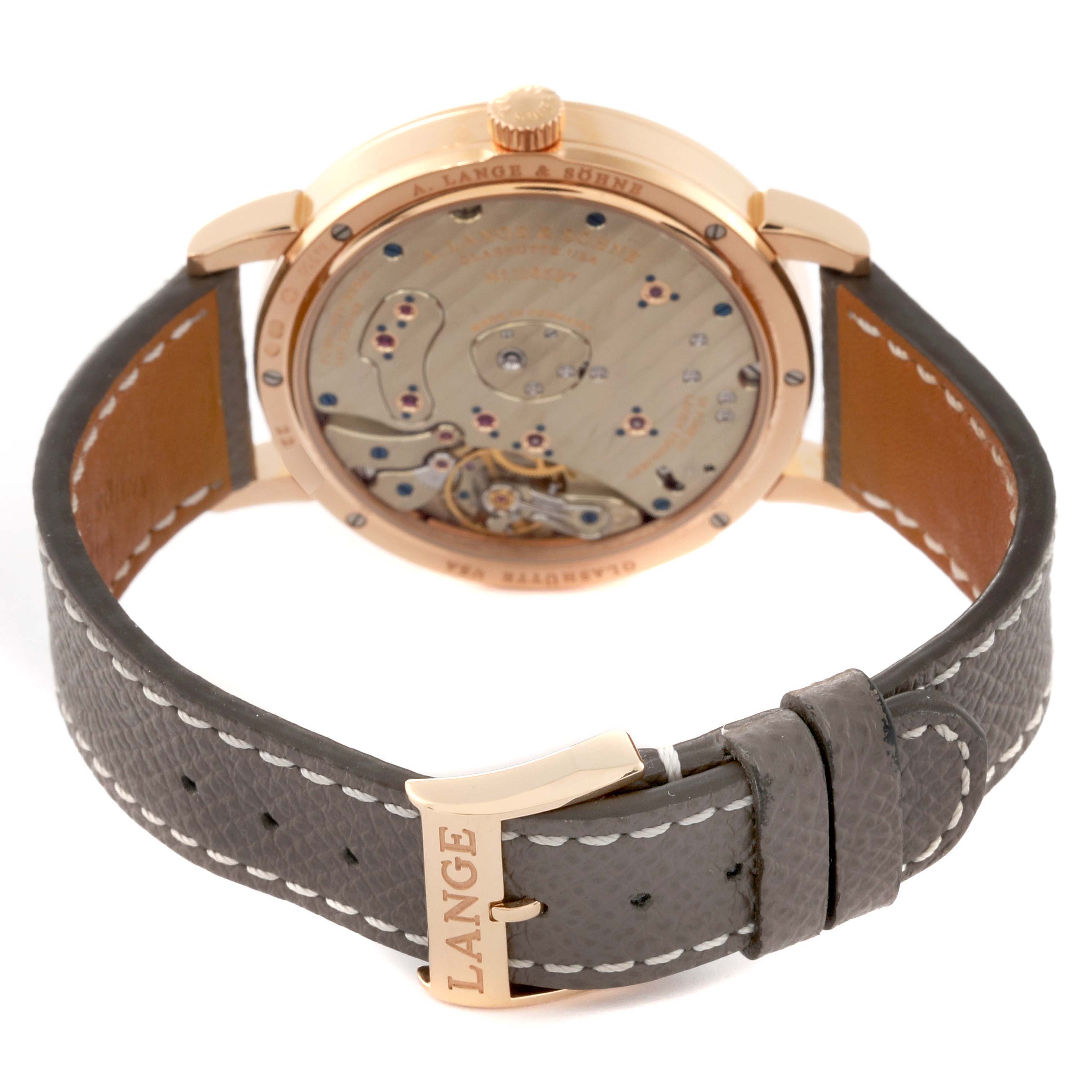 The image shows the rear view of the Lange 1 model by A. Lange 
Söhne, displaying the movement and leather strap with branded buckle.