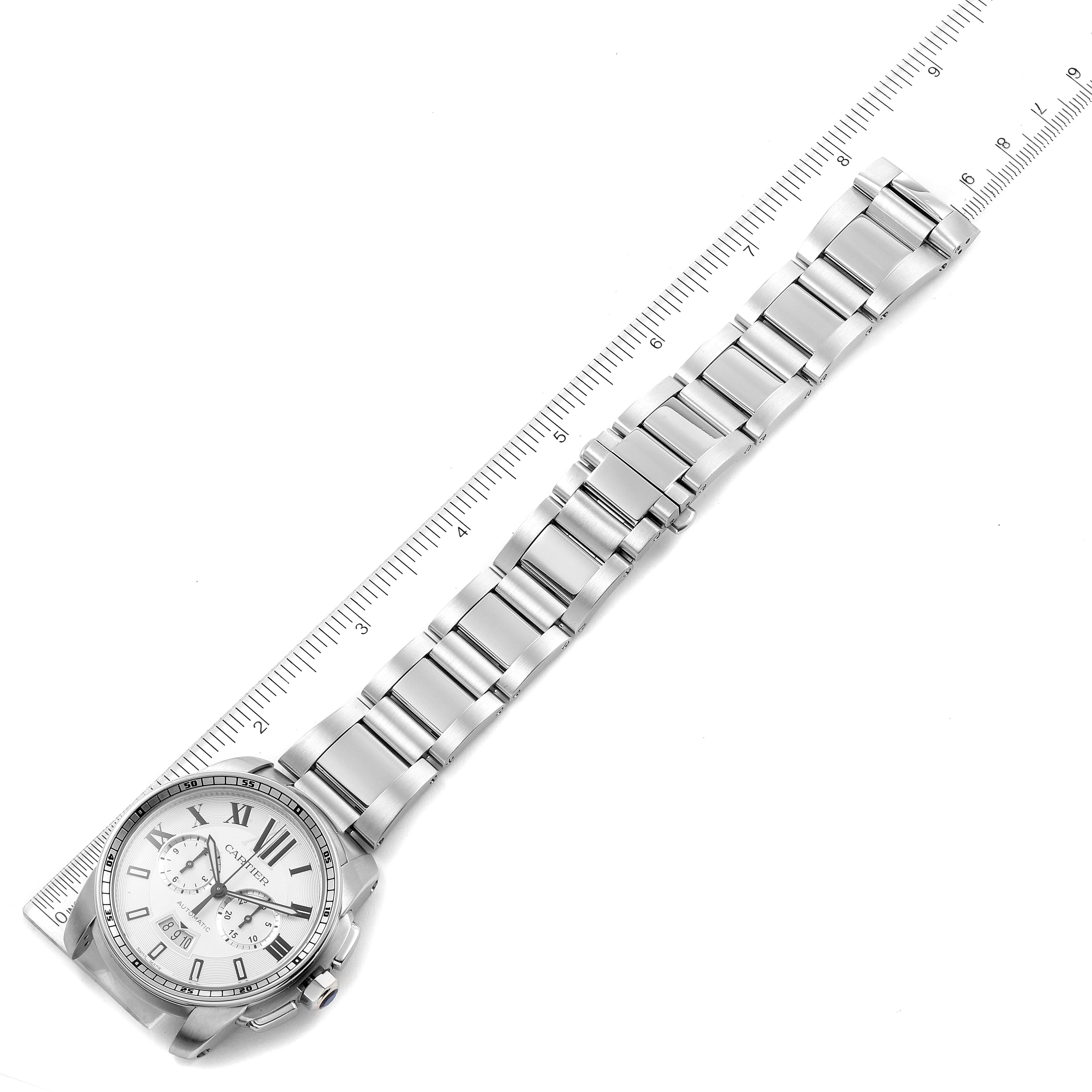 The image shows a top-down view of a Calibre de Cartier watch by Cartier, highlighting its face and metal bracelet alongside a ruler.
