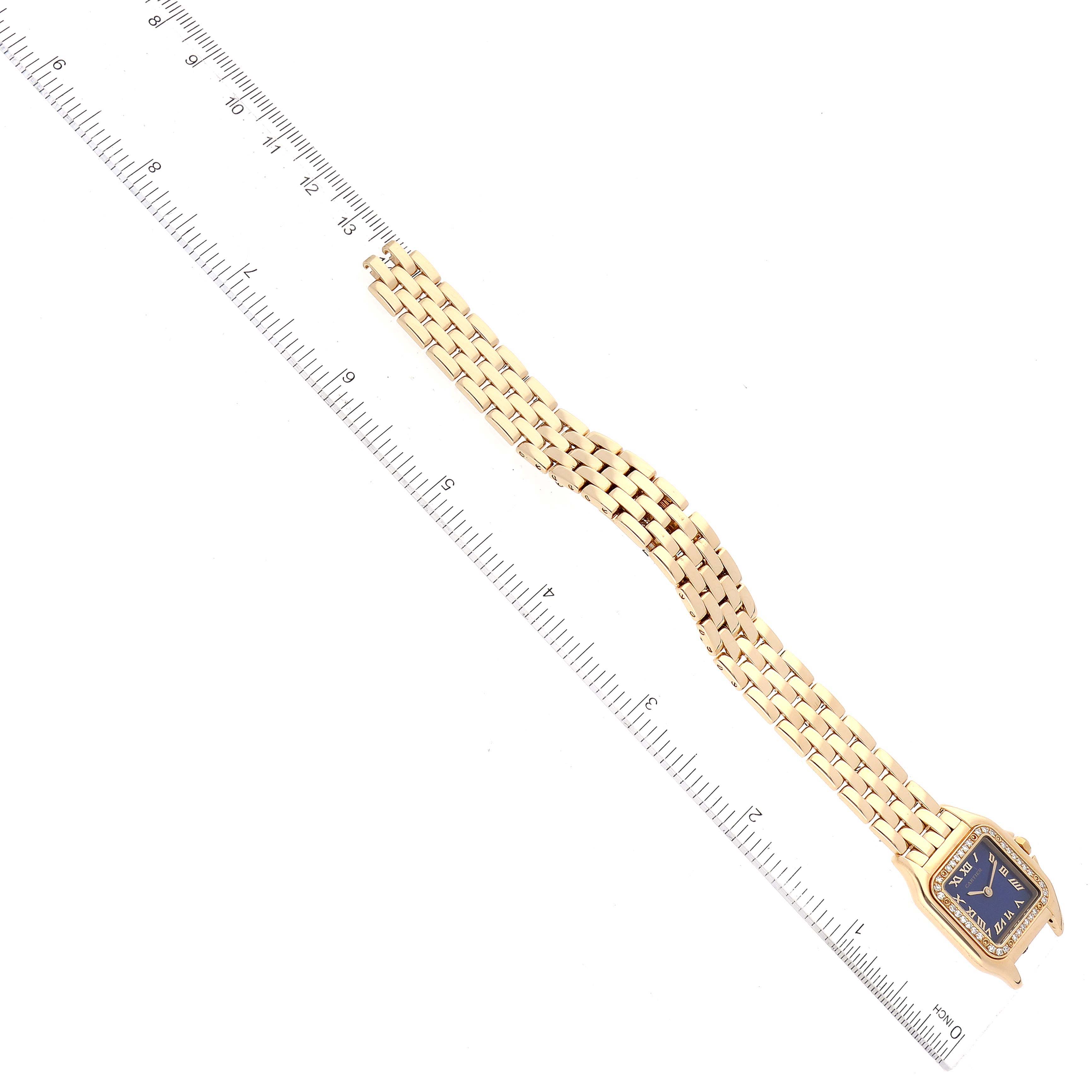 The Cartier Panthere 8057915 Women's Yellow Gold Blue Dial 8057915 Women's Yellow Gold Blue Dial watch is shown from a top-down angle, highlighting its gold bracelet and rectangular blue dial next to a ruler.