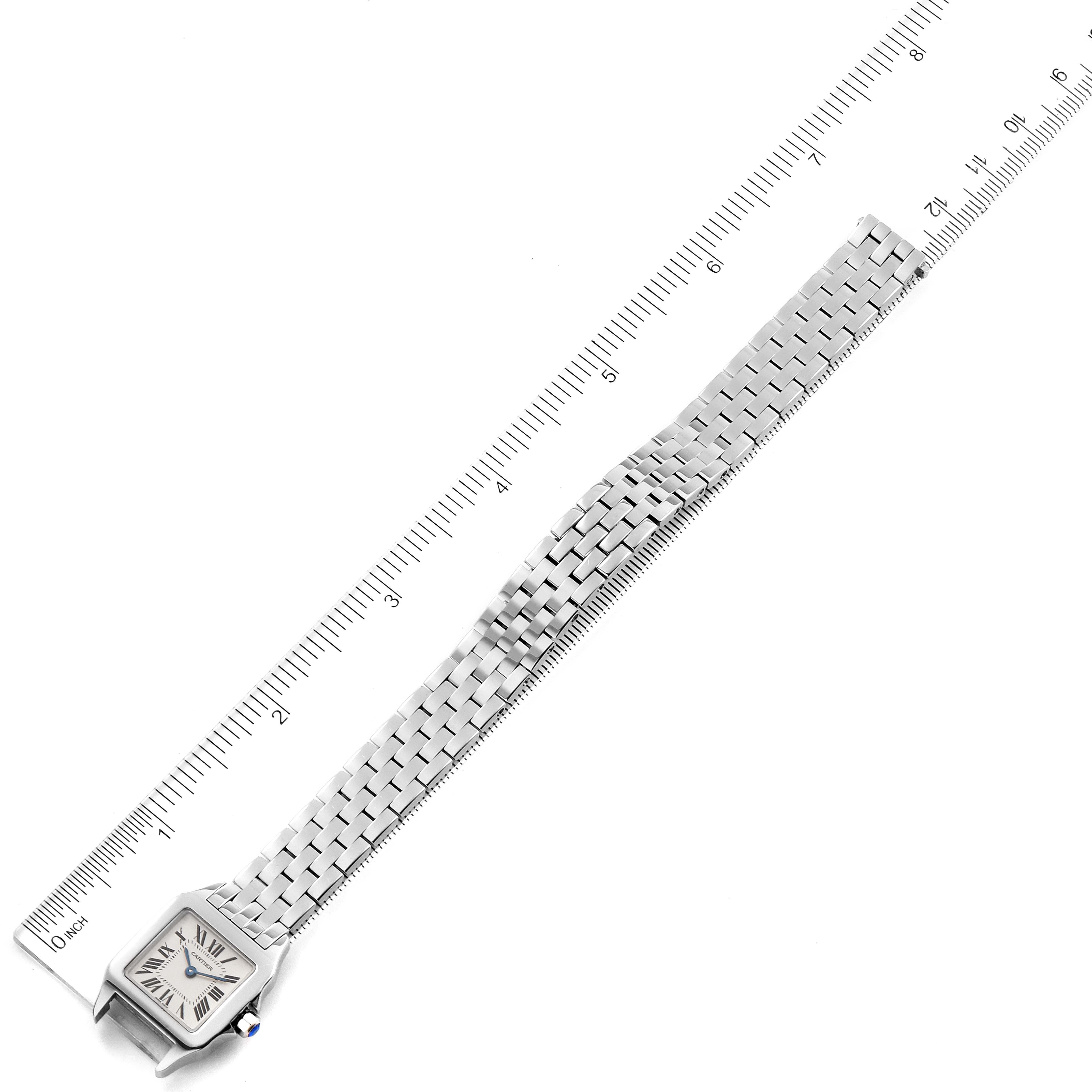 The image shows the entire Santos Demoiselle model by Cartier, including the watch face and the fully extended metal bracelet, laid next to a ruler.