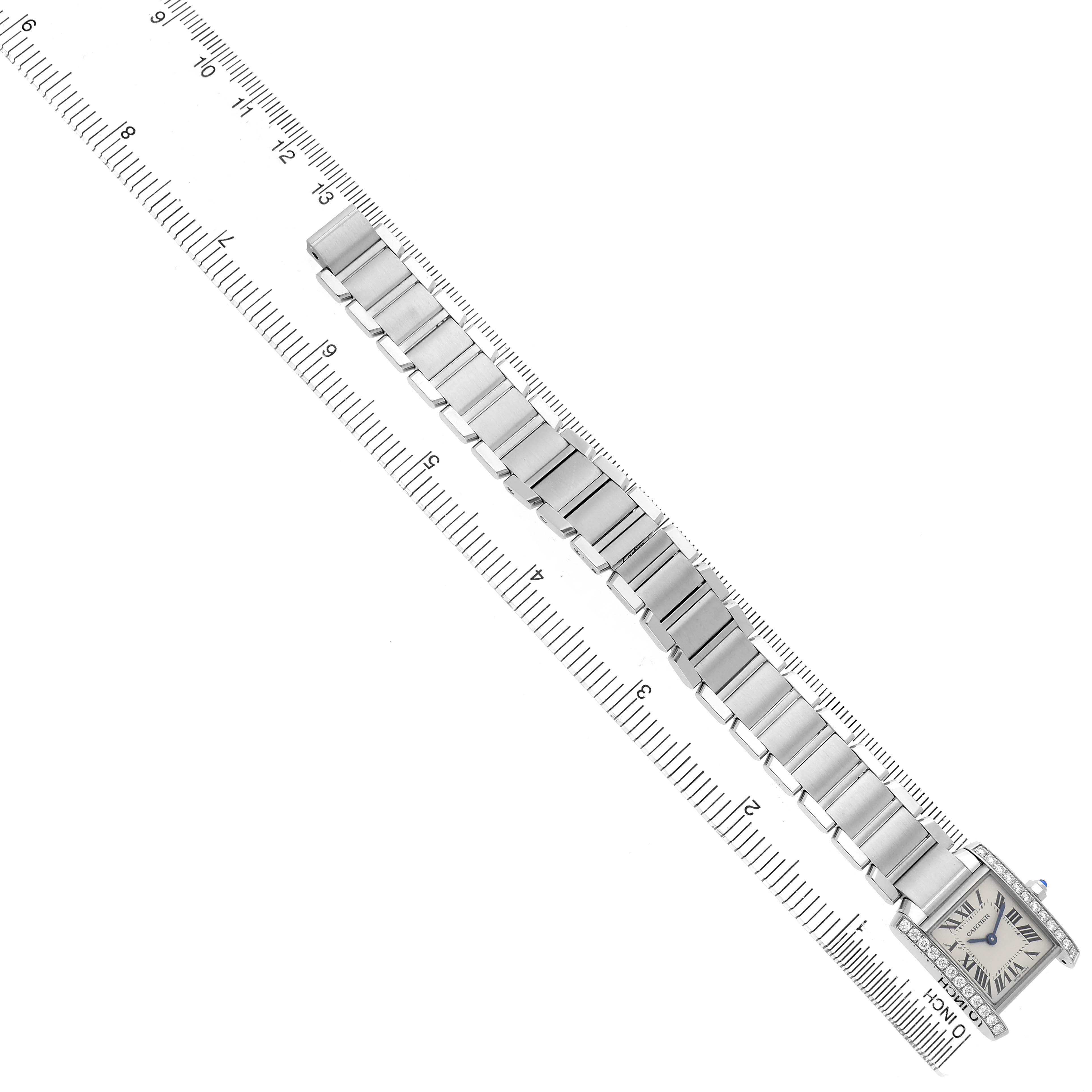 The Cartier Tank Française watch is shown from a top-down angle, highlighting its bracelet and face next to a ruler.
