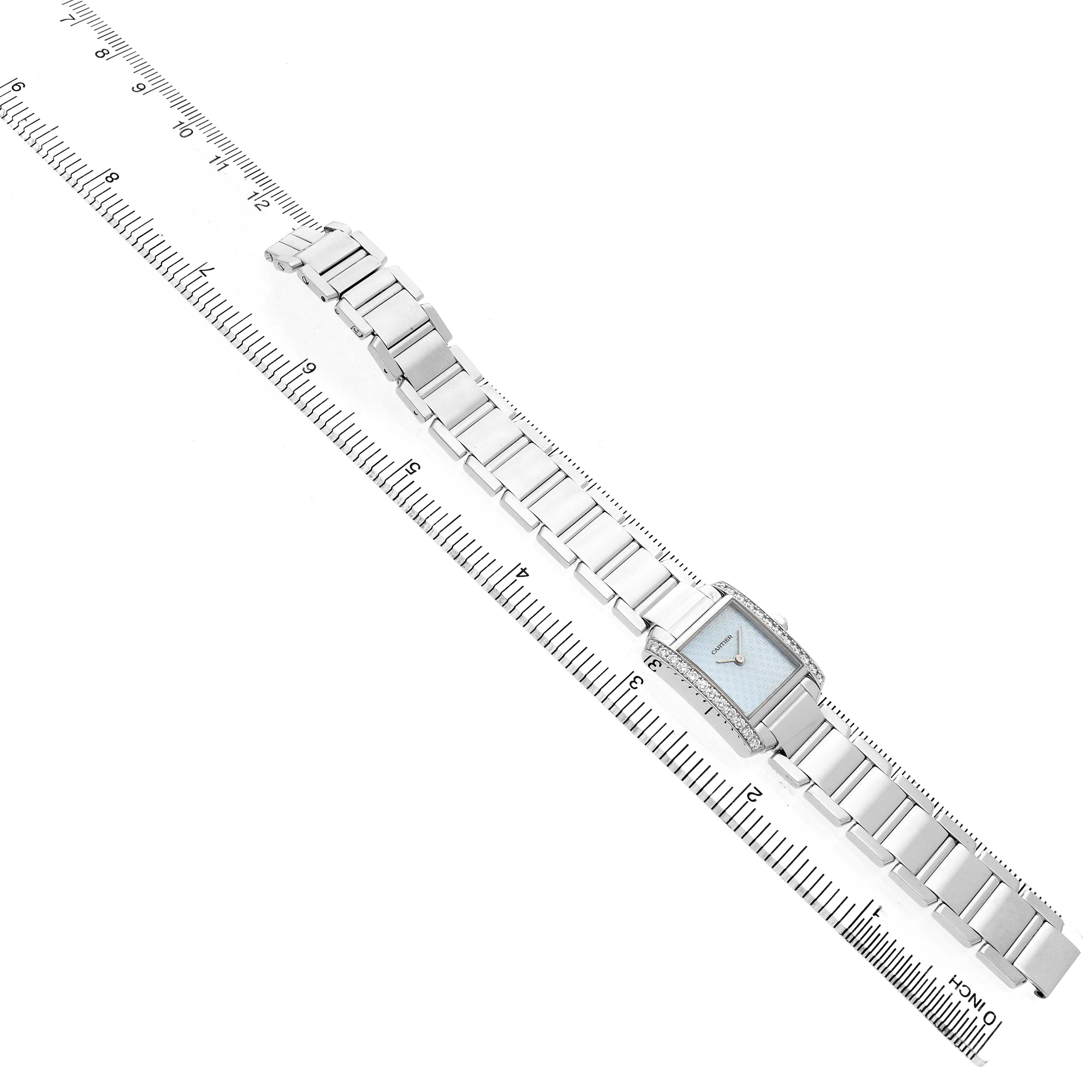 The Cartier Tank Française watch is shown from a top angle, with its bracelet fully extended alongside a measuring ruler.