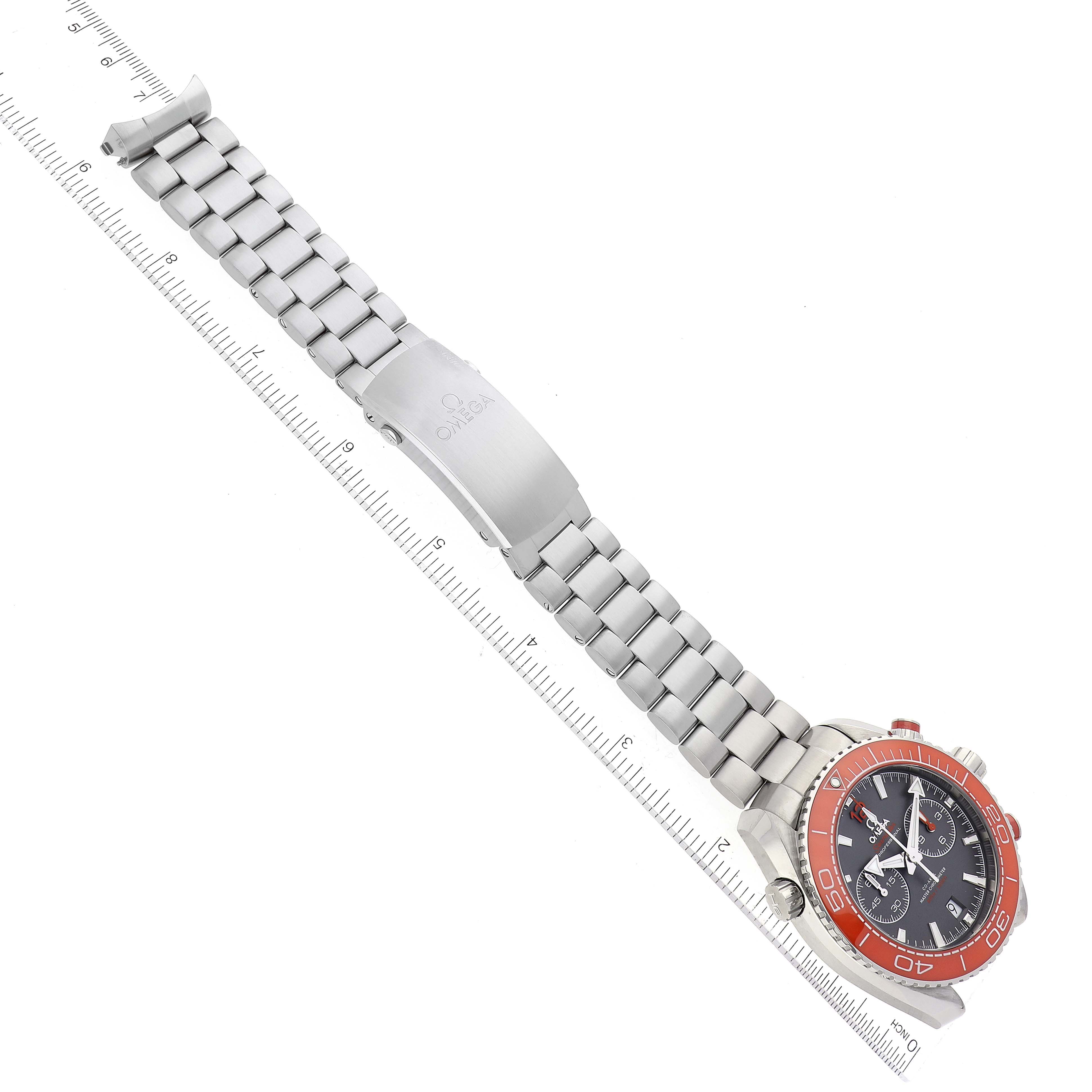 The image shows the Omega Planet Ocean 215.30.46.51.99.001 Men's Stainless Steel Grey Dial 215.30.46.51.99.001 Men's Stainless Steel Grey Dial watch laid flat, highlighting its stainless steel band, clasp, and a red bezel.