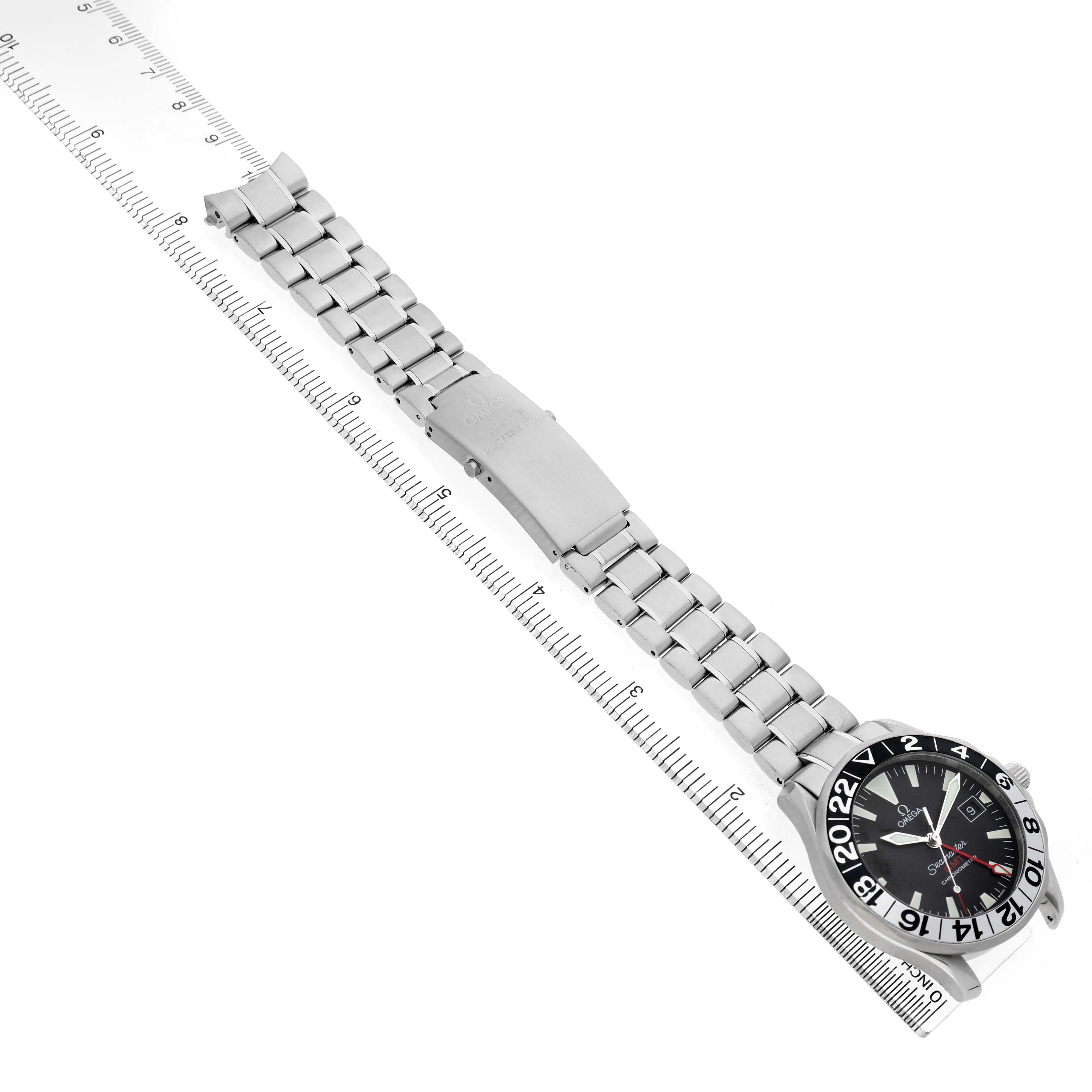 The Omega Seamaster 2234.50.00 Men's Stainless Steel Black Dial watch is shown from a top angle, displaying the watch face, bezel, bracelet, and clasp beside a ruler.