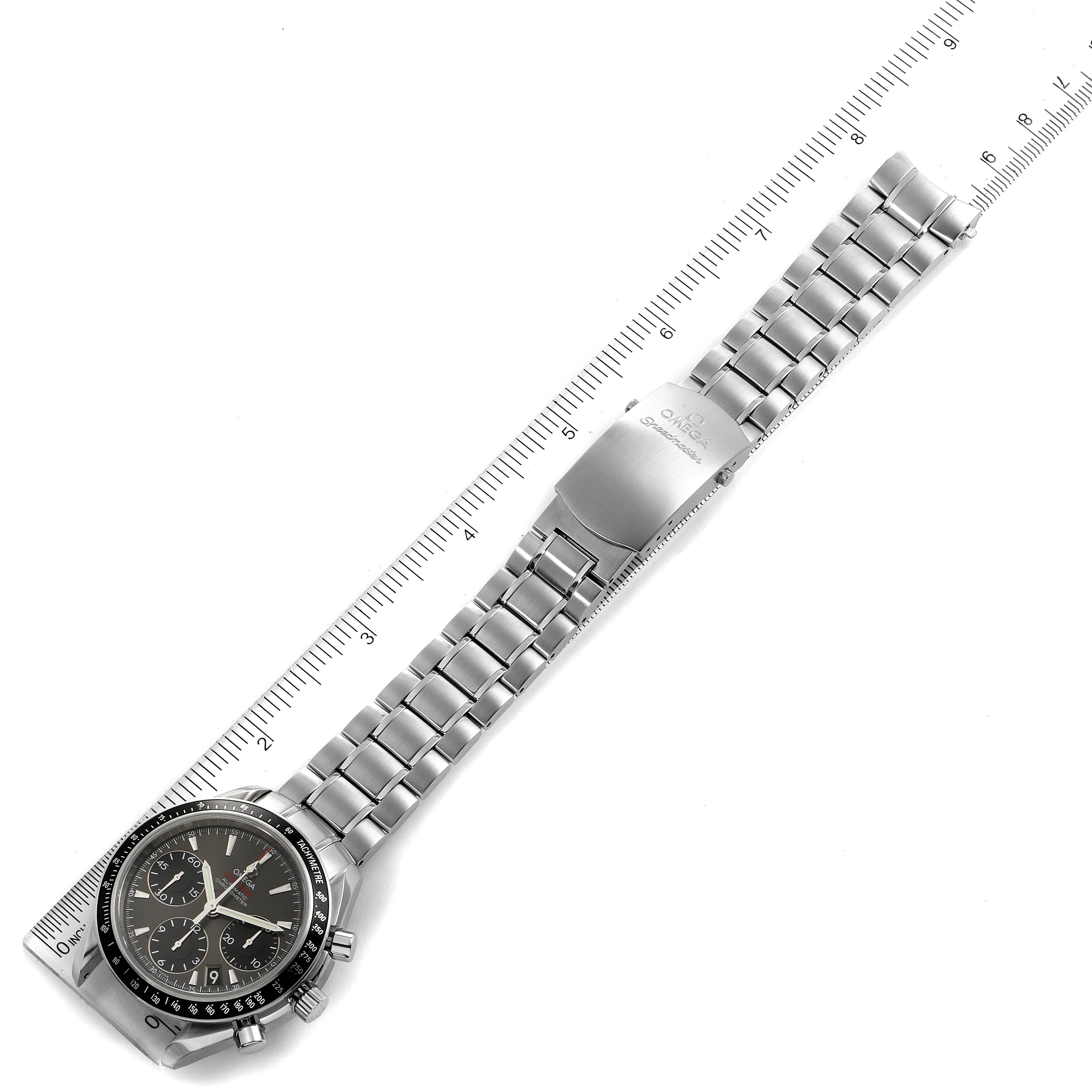 The image shows an Omega Speedmaster 323.30.40.40.06.001 Men
s Stainless Steel Grey Dial 323.30.40.40.06.001 Men
s Stainless Steel Grey Dial watch laid flat, displaying the dial, chronograph buttons, and metal bracelet alongside a ruler.