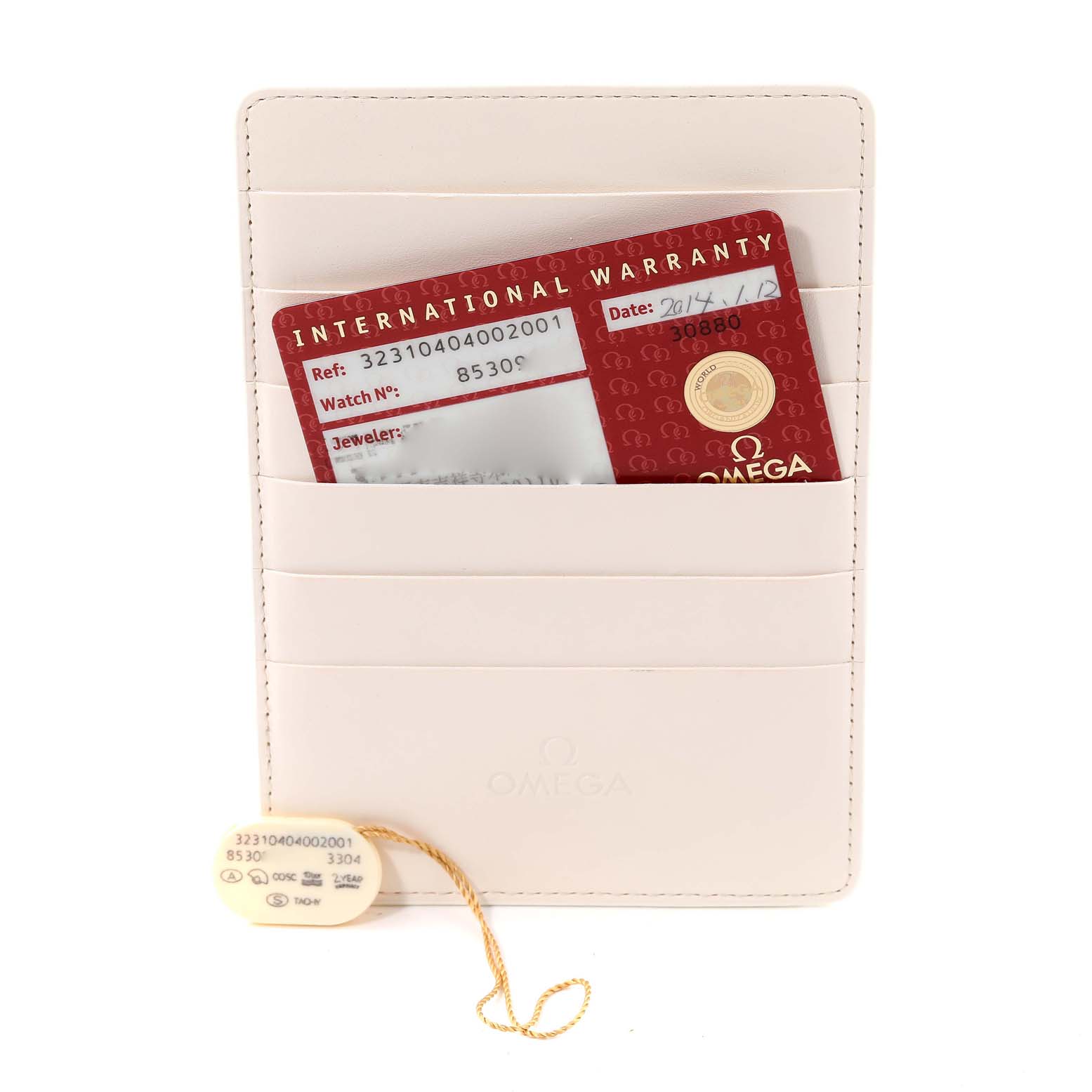 The image shows an Omega Speedmaster 323.10.40.40.02.001 Men's Stainless Steel Silver Dial 323.10.40.40.02.001 Men's Stainless Steel Silver Dial International Warranty card inside a beige cardholder, along with a model tag attached by a string.