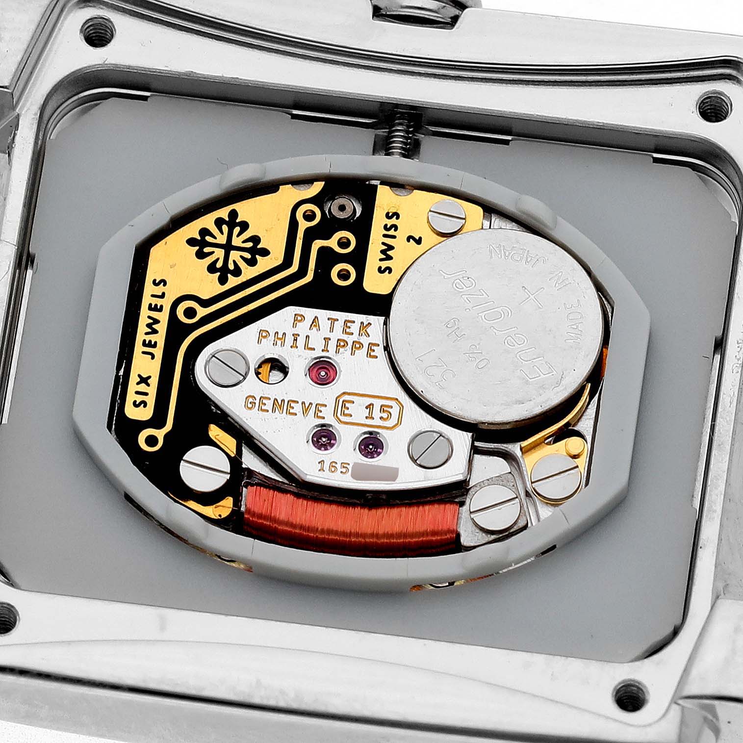 The image shows an interior view of the Patek Philippe Twenty-4 4910/10A-010 Women's Stainless Steel Grey Dial watch, highlighting the movement components and battery.