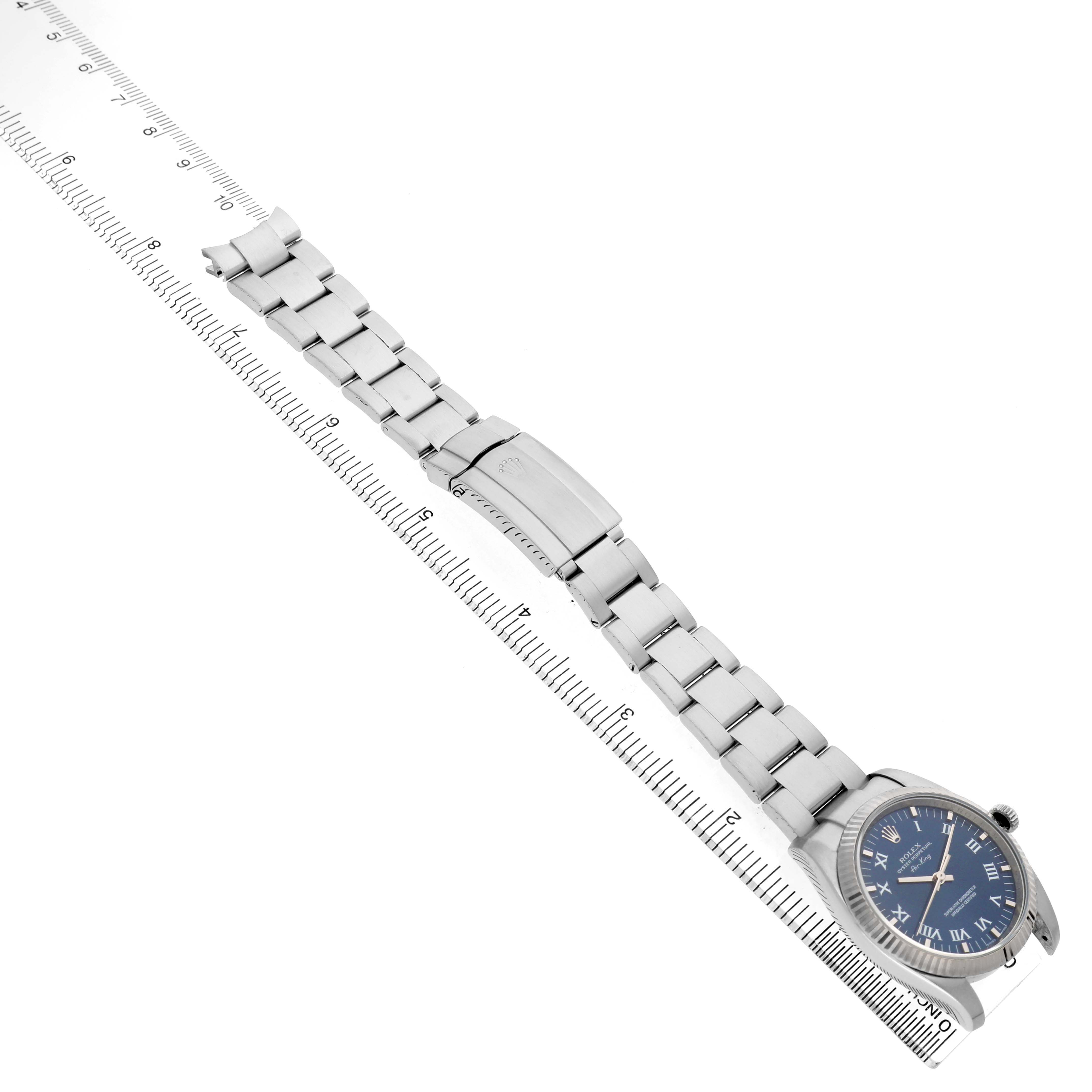The Rolex Air-King 114234 Men's Stainless Steel Blue Dial watch is shown from a top view, displaying the full band and watch face alongside a ruler for scale.