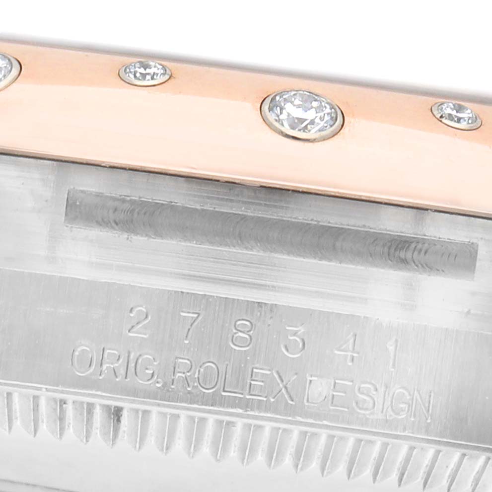 This image shows a close-up of the engraved side of a Rolex Mid-Size M278341RBR-0016 Women's Steel and Gold (two tone) Silver Dial watch, highlighting the bezel with embedded diamonds.