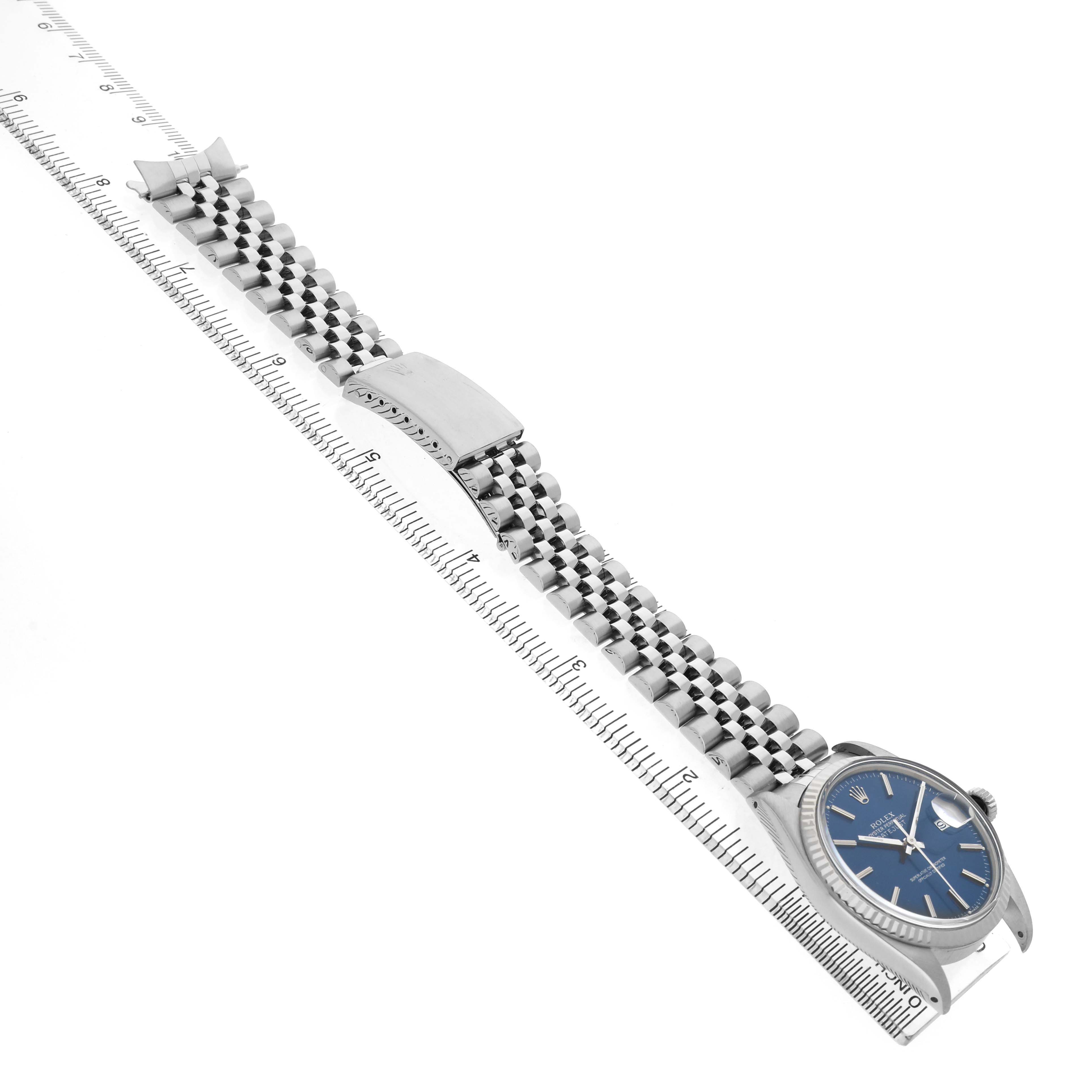 The Rolex Datejust 16014 Men's Steel and Gold (two tone) Blue Dial watch is shown at a diagonal angle, highlighting its bracelet, clasp, and blue dial with a ruler for scale.