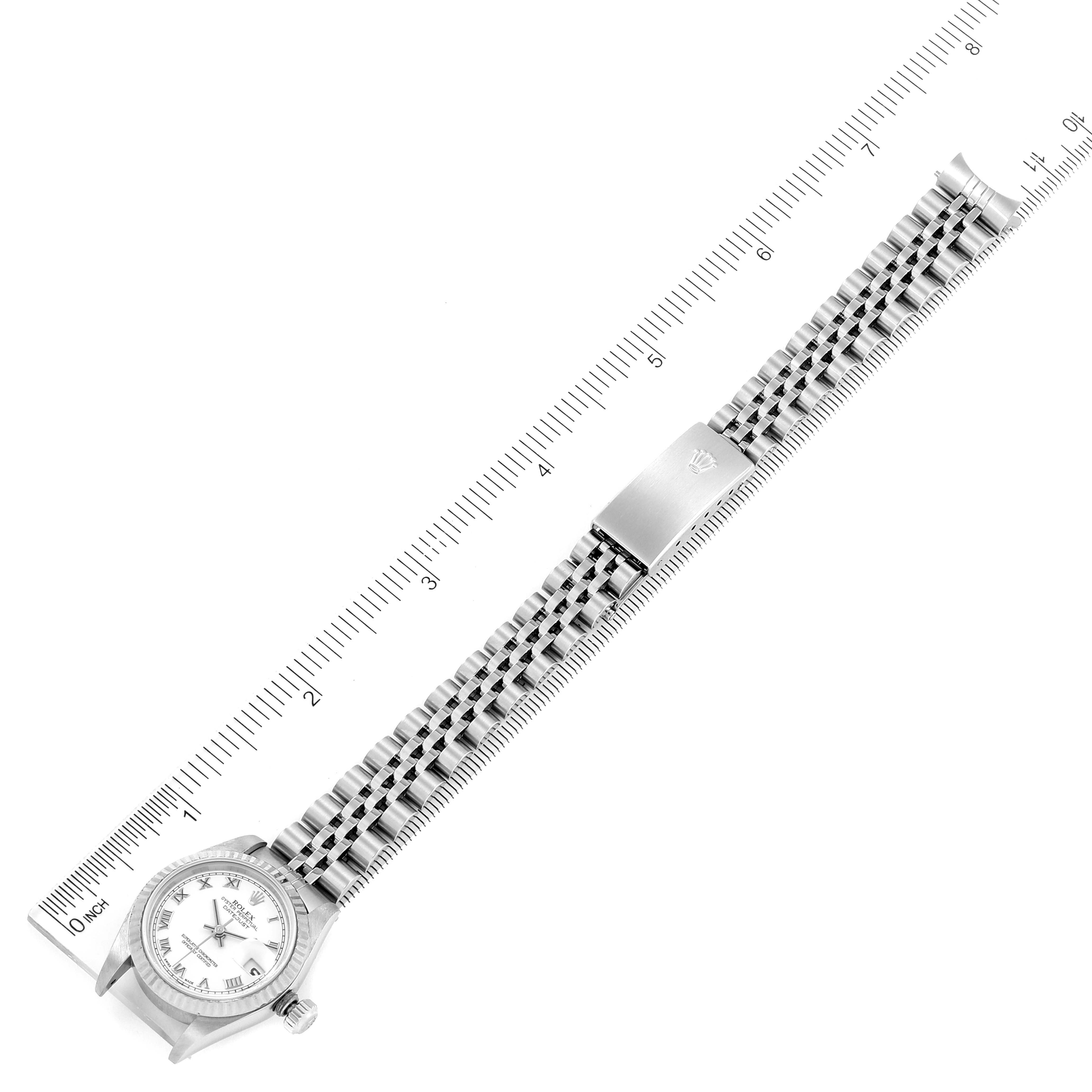 The image shows a top-down view of a Rolex Datejust 79174 Women's Stainless Steel White Dial 79174 Women's Stainless Steel White Dial watch with its face and full bracelet laid flat against a ruler.