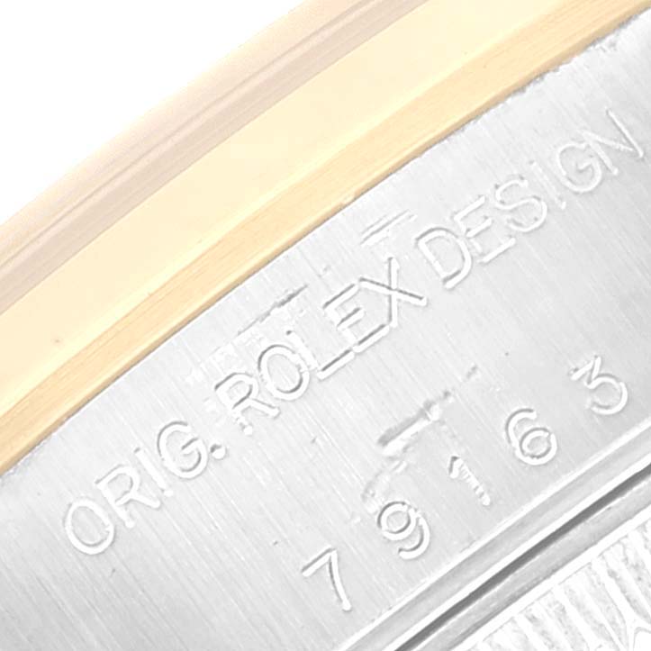 The image shows a close-up of the engraved text on the case of a Rolex Datejust 79163 Women's Steel and Gold (two tone) Grey Dial 79163 Women's Steel and Gold (two tone) Grey Dial watch, including the design and model number.