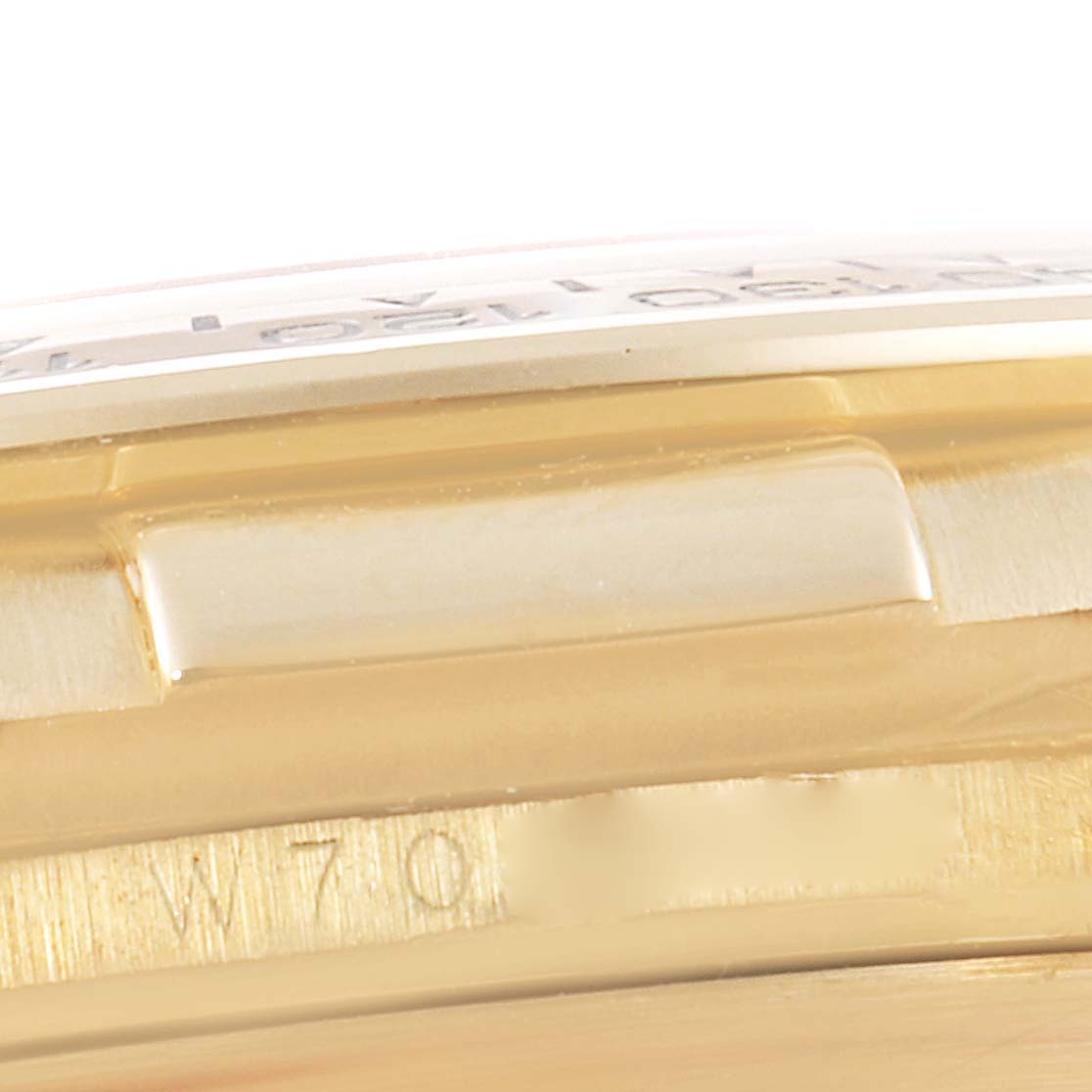 This image shows a close-up of the side of a Rolex Daytona 16518 Men's Yellow Gold White Dial 16518 Men's Yellow Gold White Dial watch case, highlighting part of the bezel and engraving.
