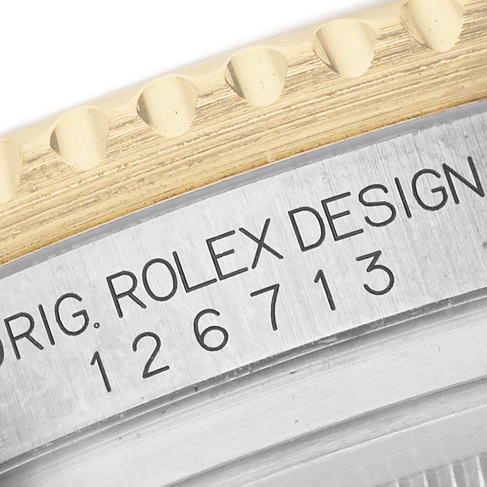 The image shows a close-up of the Rolex GMT-Master 126713GRNR Men's Steel and Gold (two tone) Black Dial's case side, displaying the reference number and part of the fluted bezel.