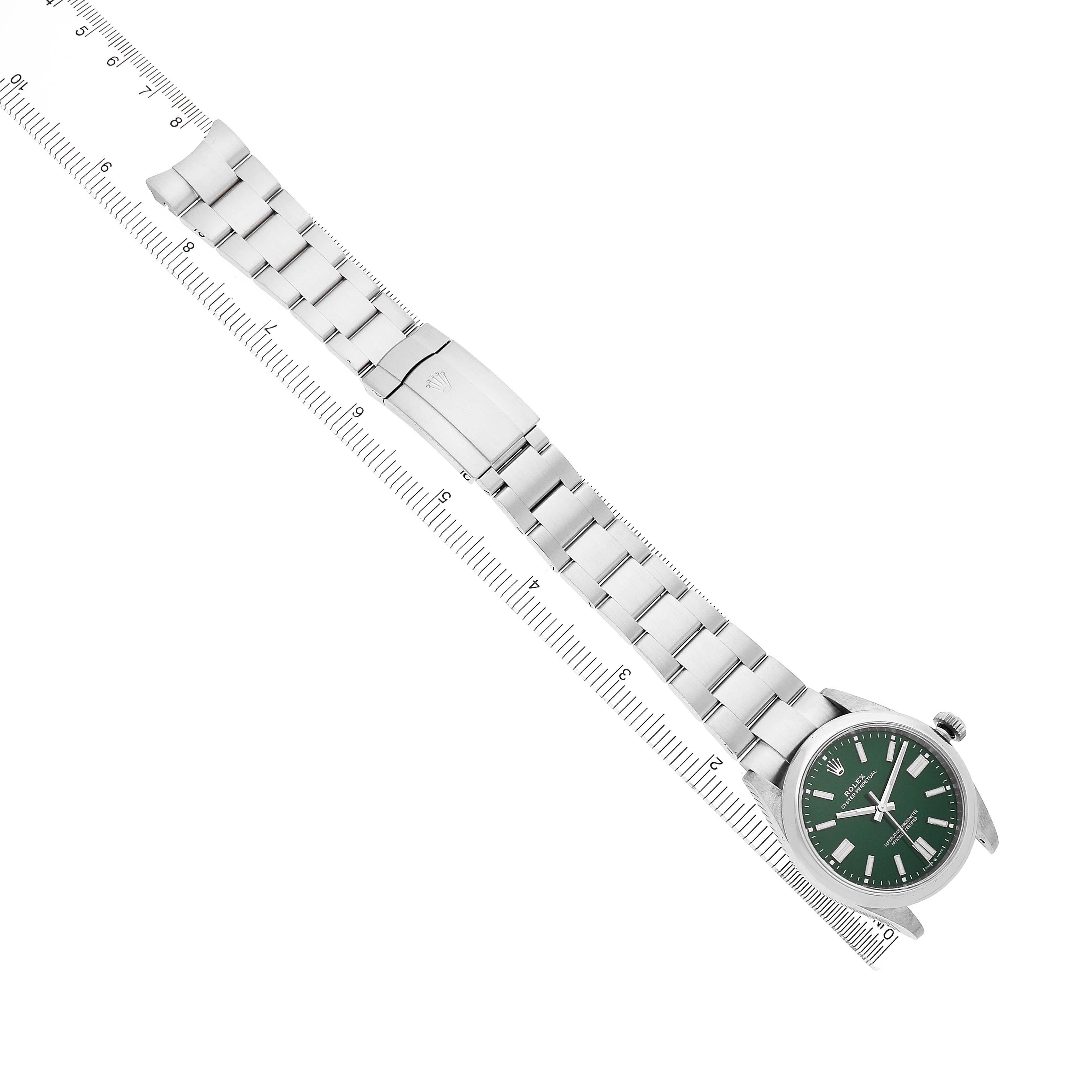 The Rolex Oyster Perpetual 134300 Men's Stainless Steel Green Dial watch is shown diagonally from above, displaying the full bracelet and green dial next to a ruler.