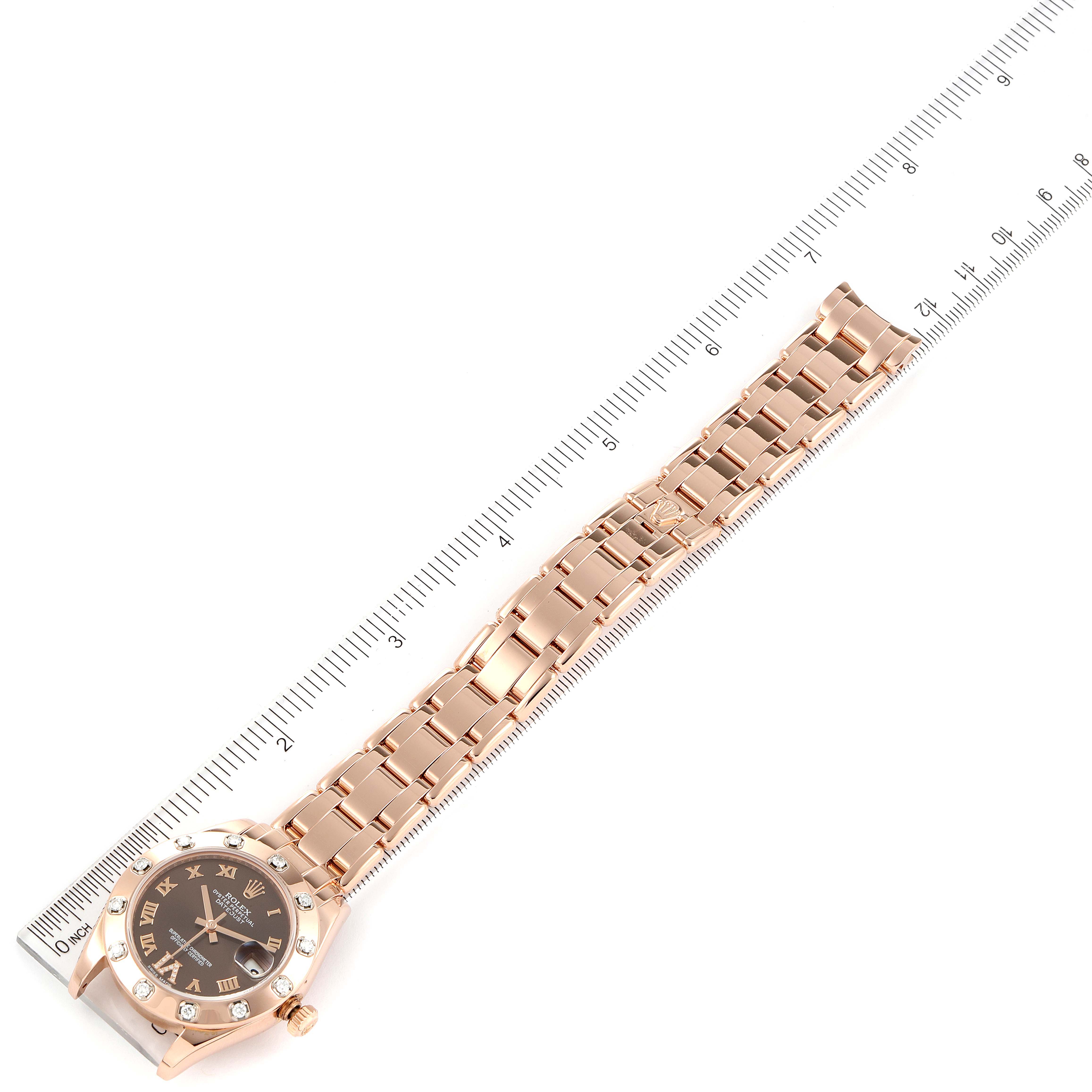 The Rolex Pearlmaster 81315 Women
s Rose Gold Brown Dial 81315 Women
s Rose Gold Brown Dial watch is shown from a top-down angle, with a focus on the entire watch and a ruler for scale.