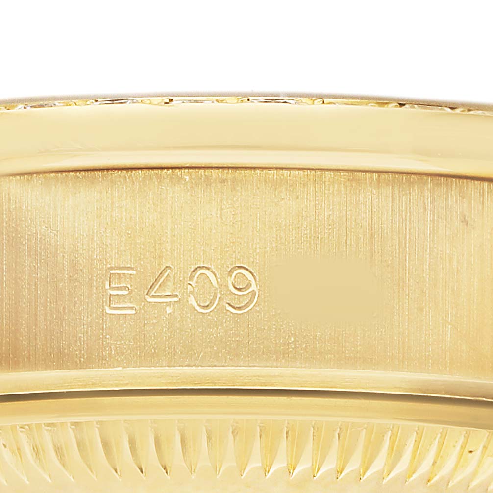 The image shows a close-up of the side of a Rolex President 69138 Women's Yellow Gold Champagne Dial model watch case, highlighting its engravings and edge detail.