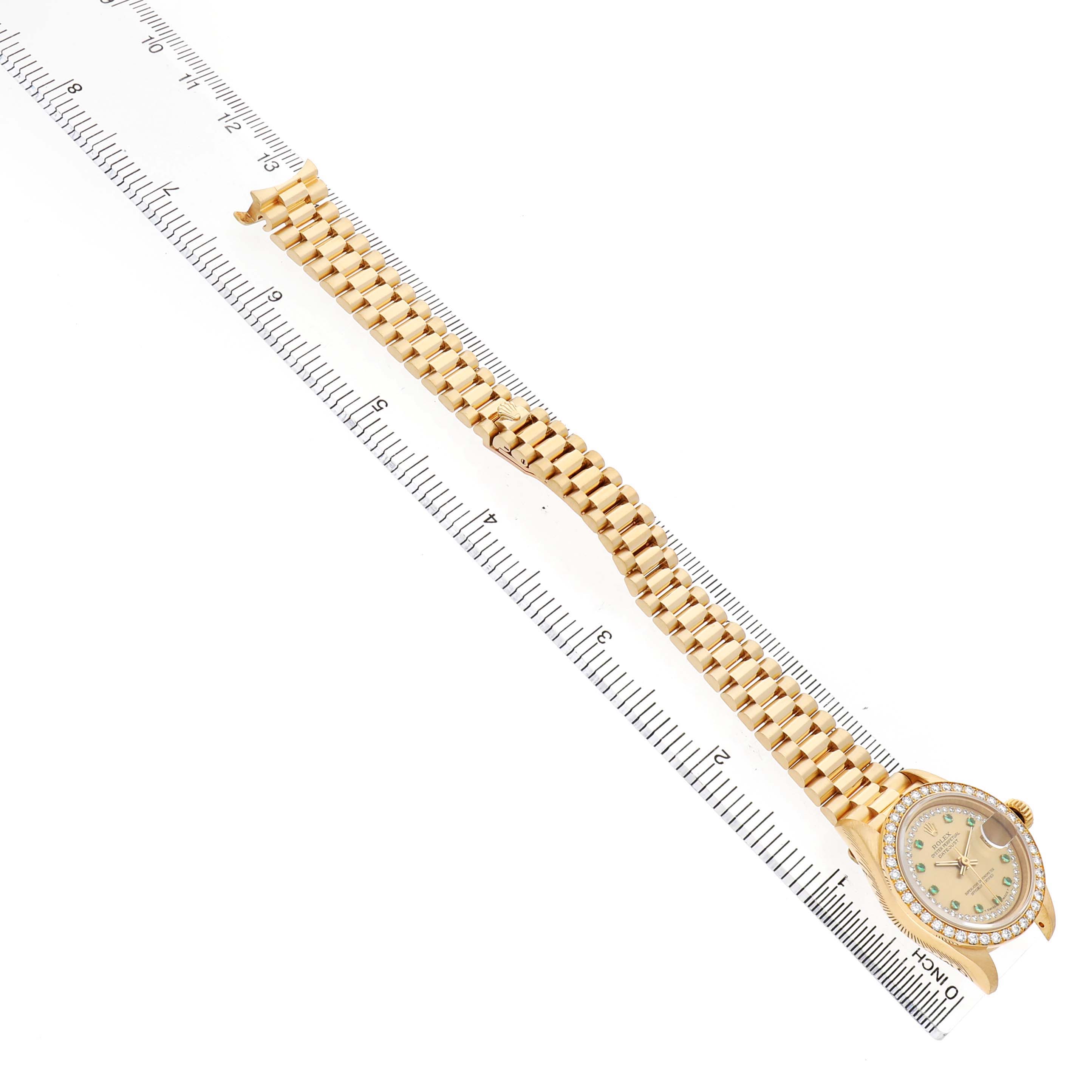 The Rolex President 69138 Women's Yellow Gold Champagne Dial model watch is displayed flat, showing the face and full gold bracelet alongside a ruler.