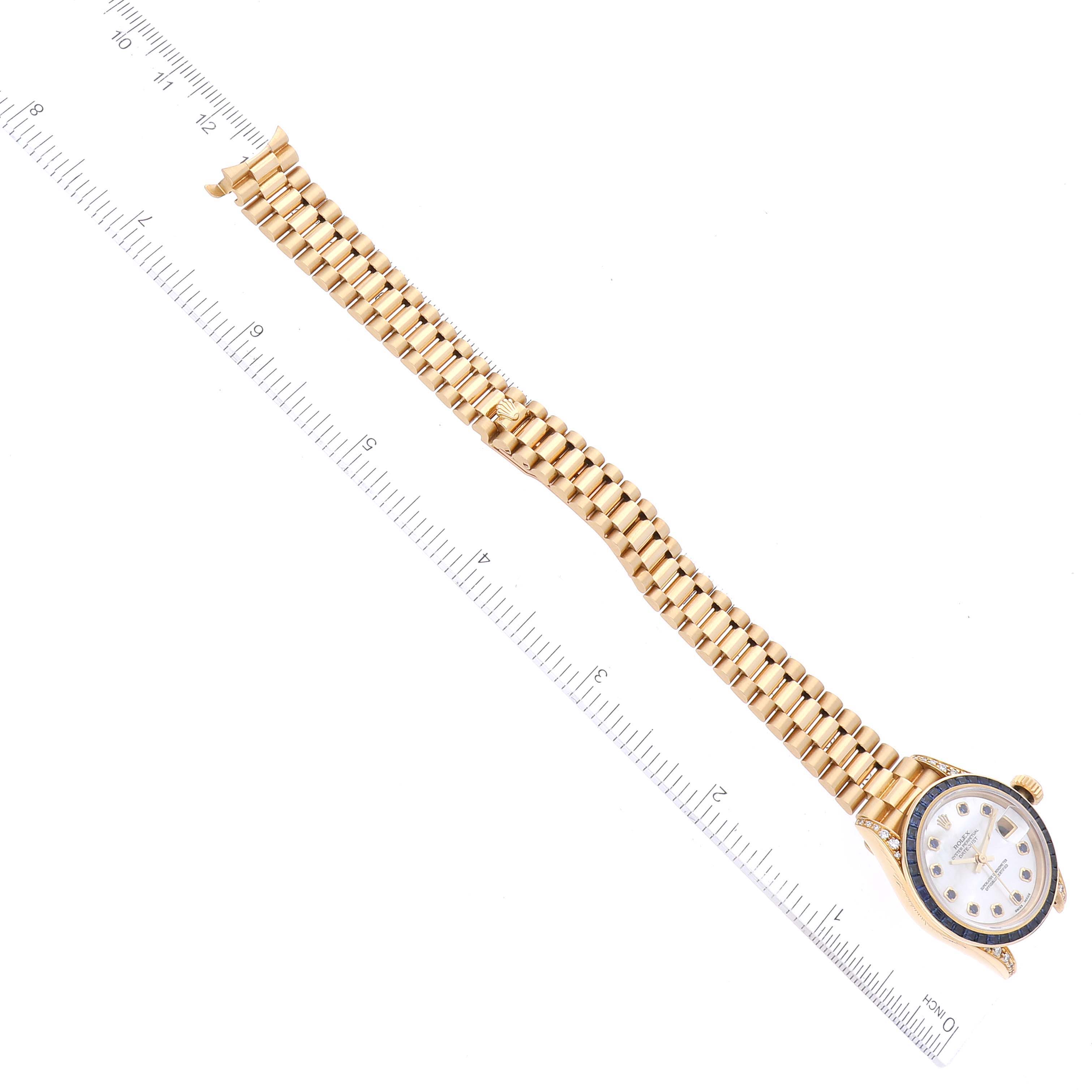 The image shows a President model Rolex watch laid flat with a ruler, highlighting its bracelet and face.