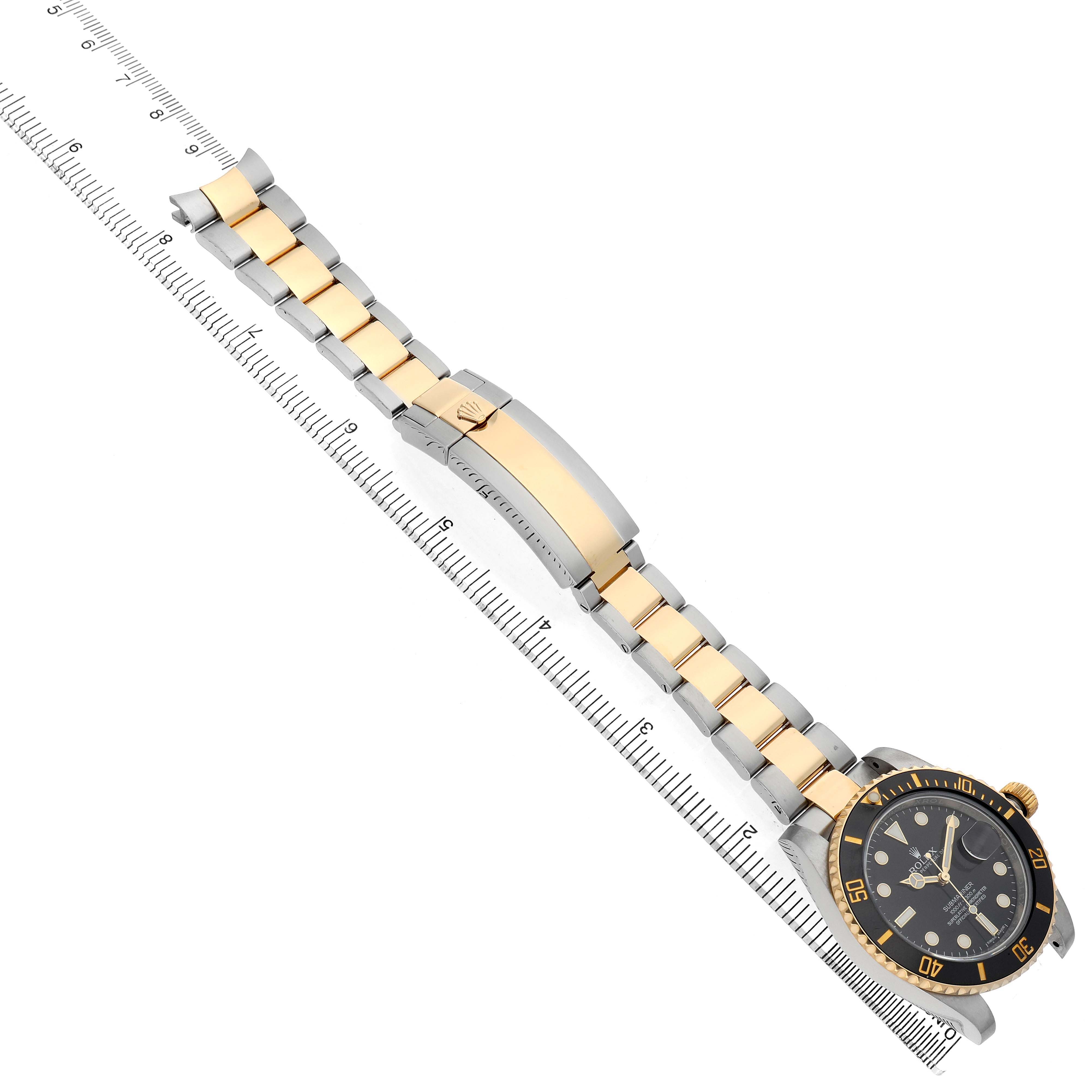 The Rolex Submariner 116613LN Men's Steel and Gold (two tone) Black Dial is shown diagonally, displaying its bracelet, clasp, dial, and bezel alongside a measuring ruler.