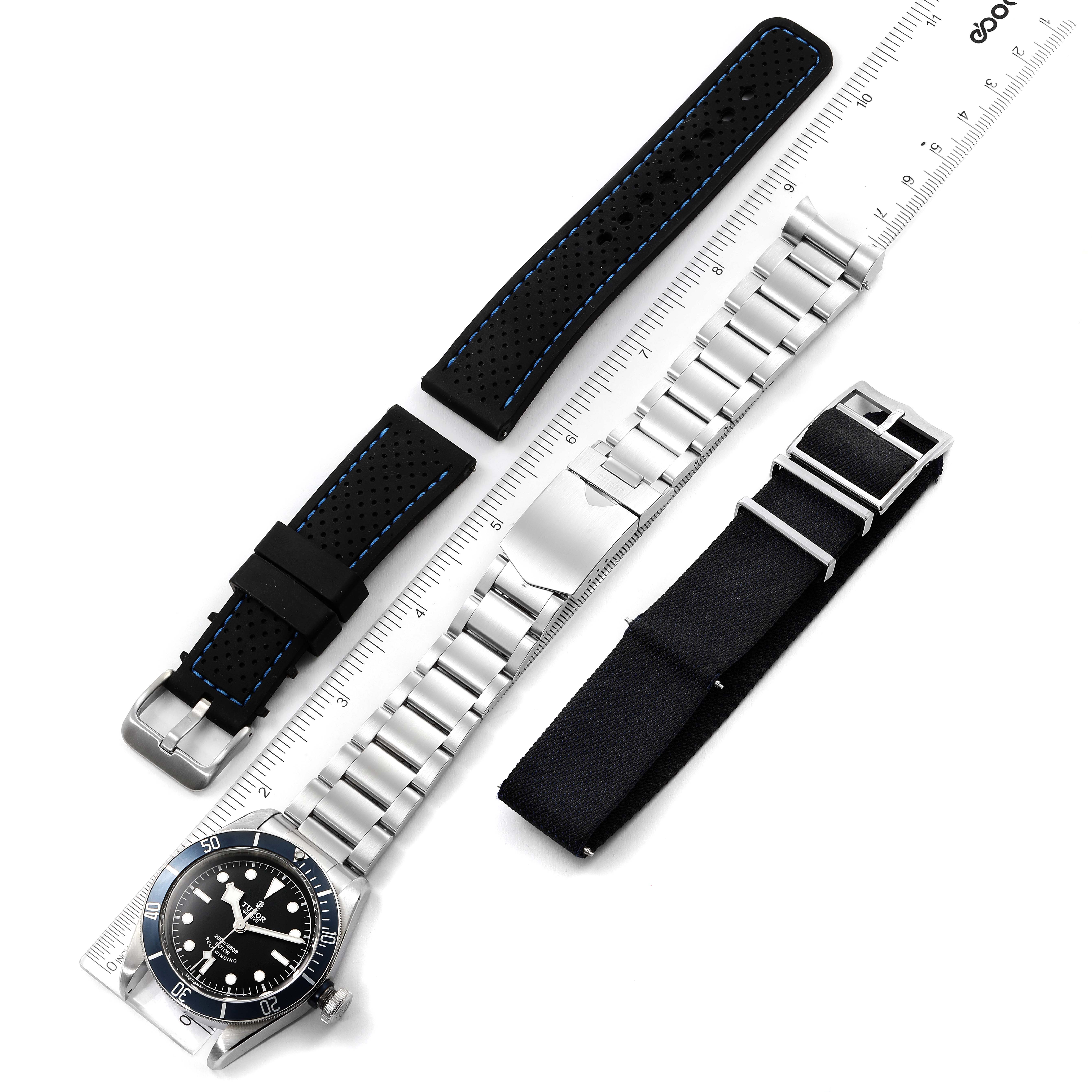 The image shows a top-down view of the Tudor Heritage Black Bay 79220 Men's Stainless Steel Black Dial 79220 Men's Stainless Steel Black Dial watch head, a metal bracelet, and two alternative straps.