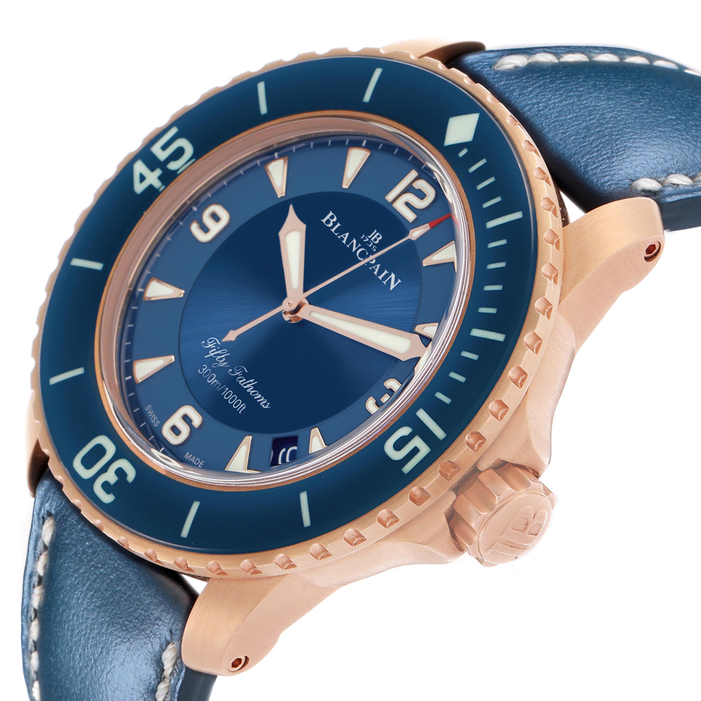 The Fifty Fathoms by Blancpain is shown at an angled close-up, highlighting the blue bezel, dial, and rose gold case.