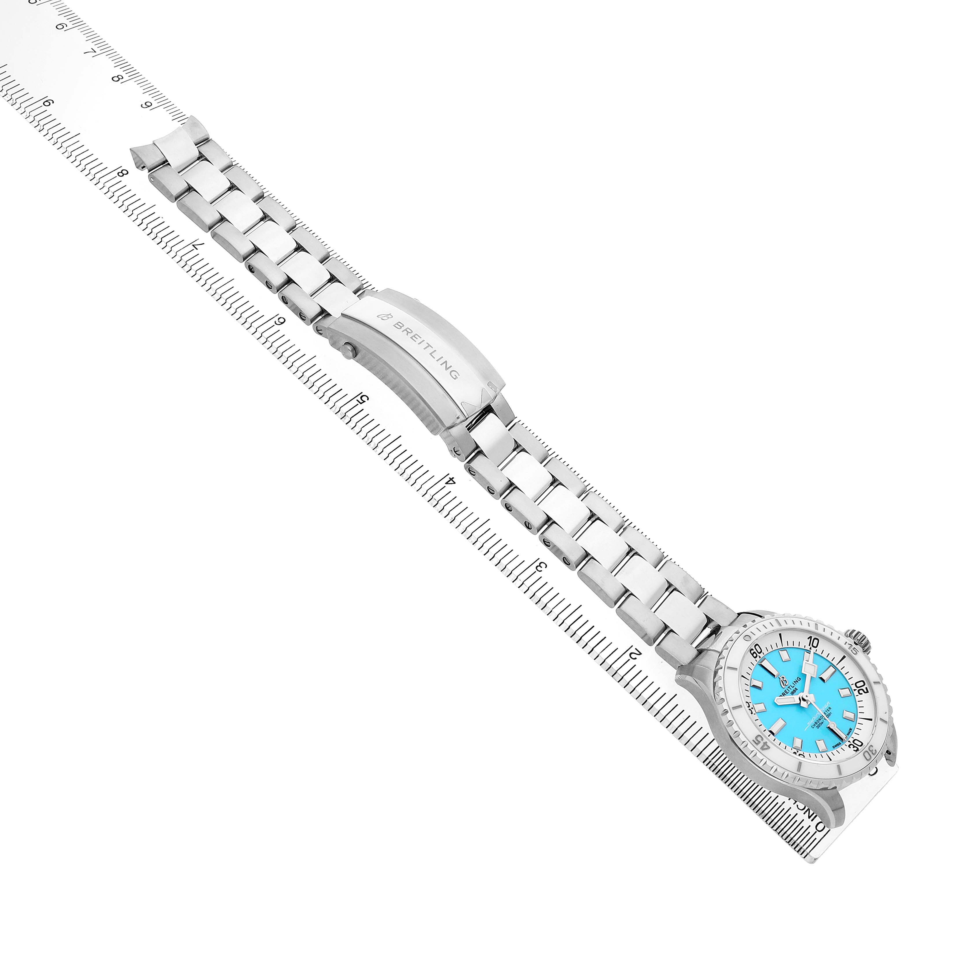 The Breitling Superocean A17377211C1A1 Men's Stainless Steel Blue Dial watch is shown from an angled top-down view, highlighting the bracelet, clasp, and turquoise dial.