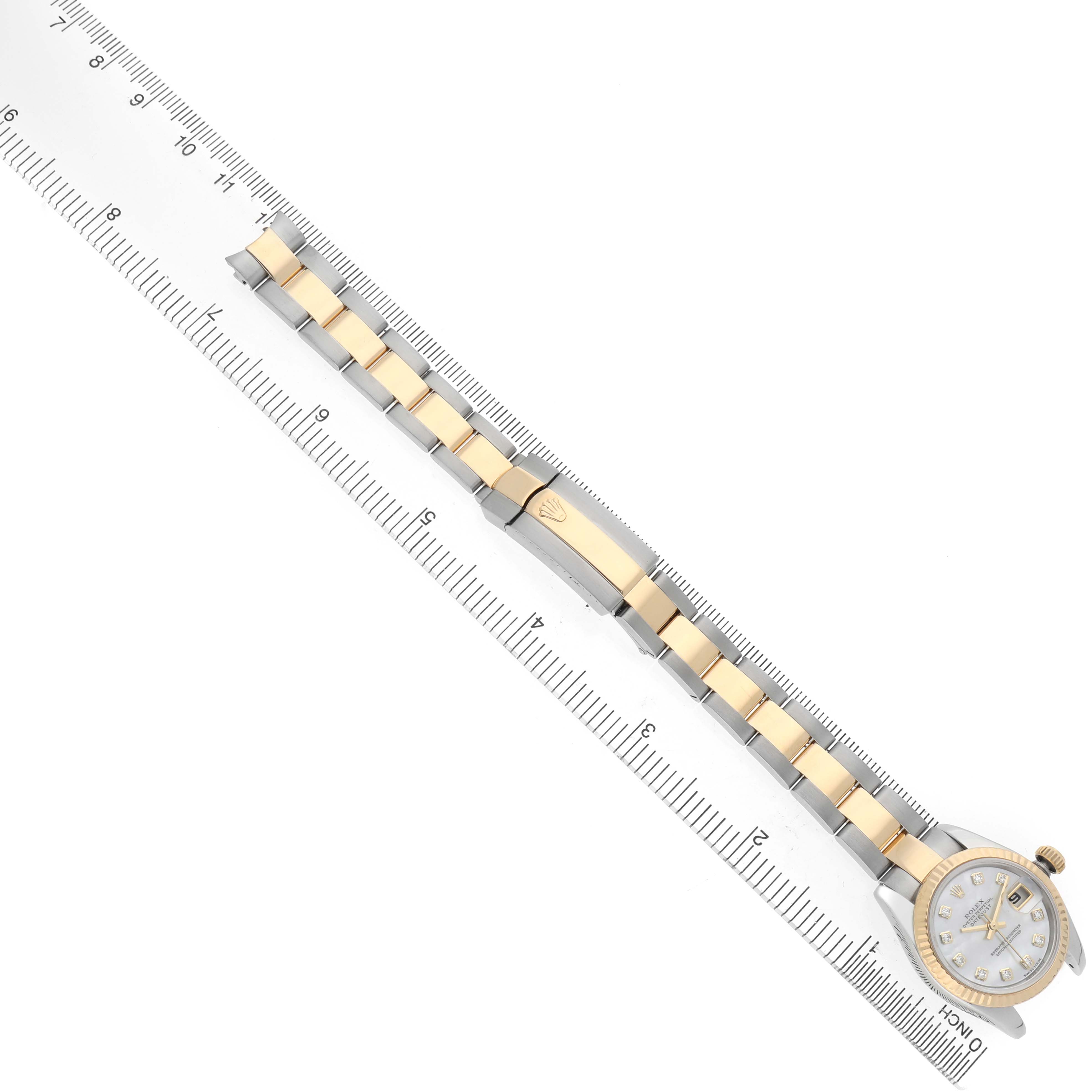 The image shows a Rolex Datejust 179173 Women's Steel and Gold (two tone) Mother of Pearl Dial watch from a top view, highlighting the bracelet, clasp, and face alongside a ruler for scale.