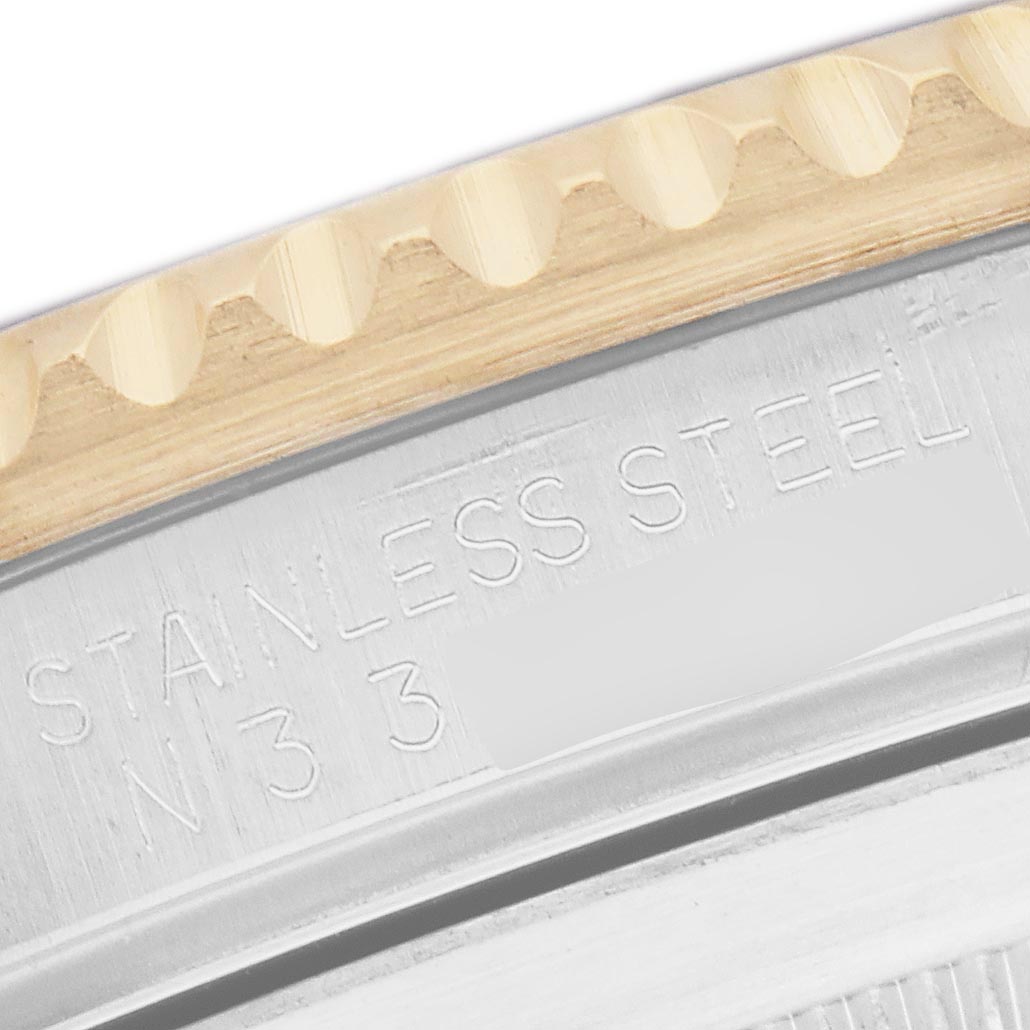 The image shows a close-up of the bezel and case back of a Rolex Submariner 16613 Men
s Steel and Gold (two tone) Champagne Dial 16613 Men
s Steel and Gold (two tone) Champagne Dial, highlighting the "STAINLESS STEEL" engraving.