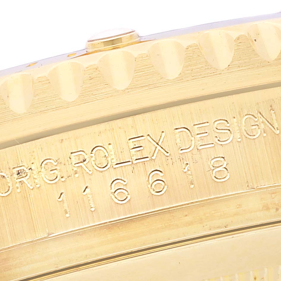 The image shows a close-up of the edge and side of a Rolex Submariner 116618 Men's Yellow Gold Blue Dial 116618 Men's Yellow Gold Blue Dial watch, featuring engraved design details.