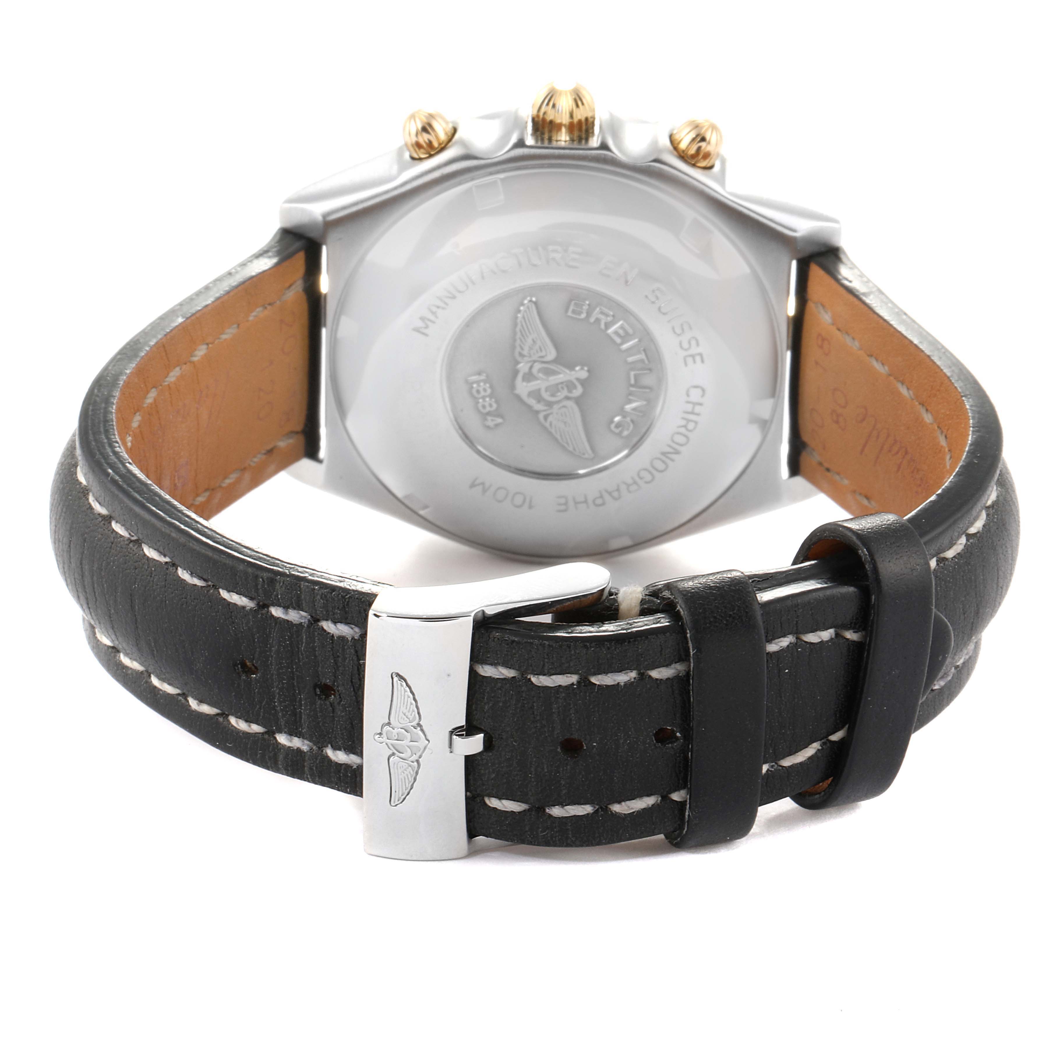 The image shows the back view of a Breitling Chronomat B13050 Men's Steel and Gold (two tone) Silver Dial B13050 Men's Steel and Gold (two tone) Silver Dial watch, featuring its case back, crown, and leather strap with stitching and buckle.